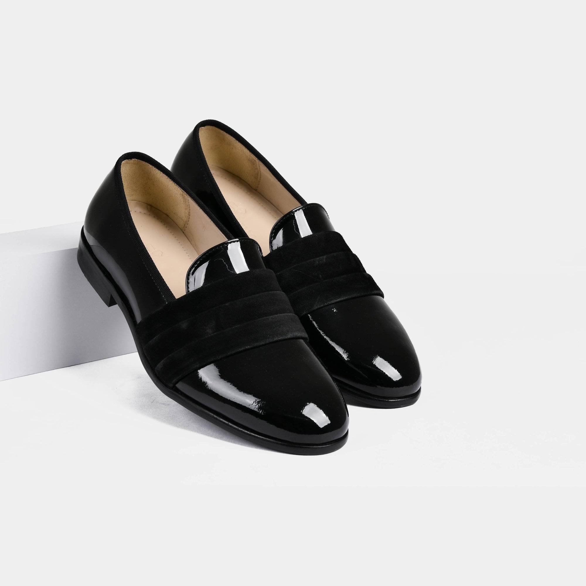 A pair of Delmar Black Patent Loafers with a suede band detail on a white background.