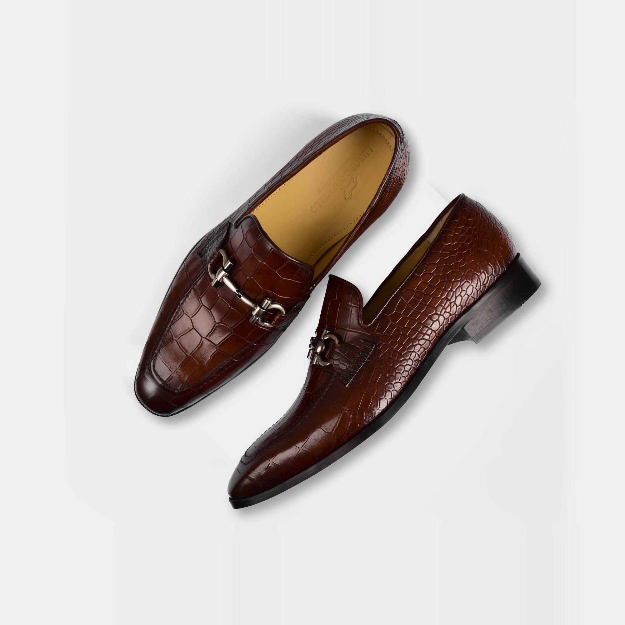 Pair of Liora Brown Leather Loafers with a crocodile skin texture and silver buckle accent, shown from above on a white background.