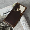 A brown leather bifold men's wallet with a white leather inlay design, laid open on a table to show its slim profile.