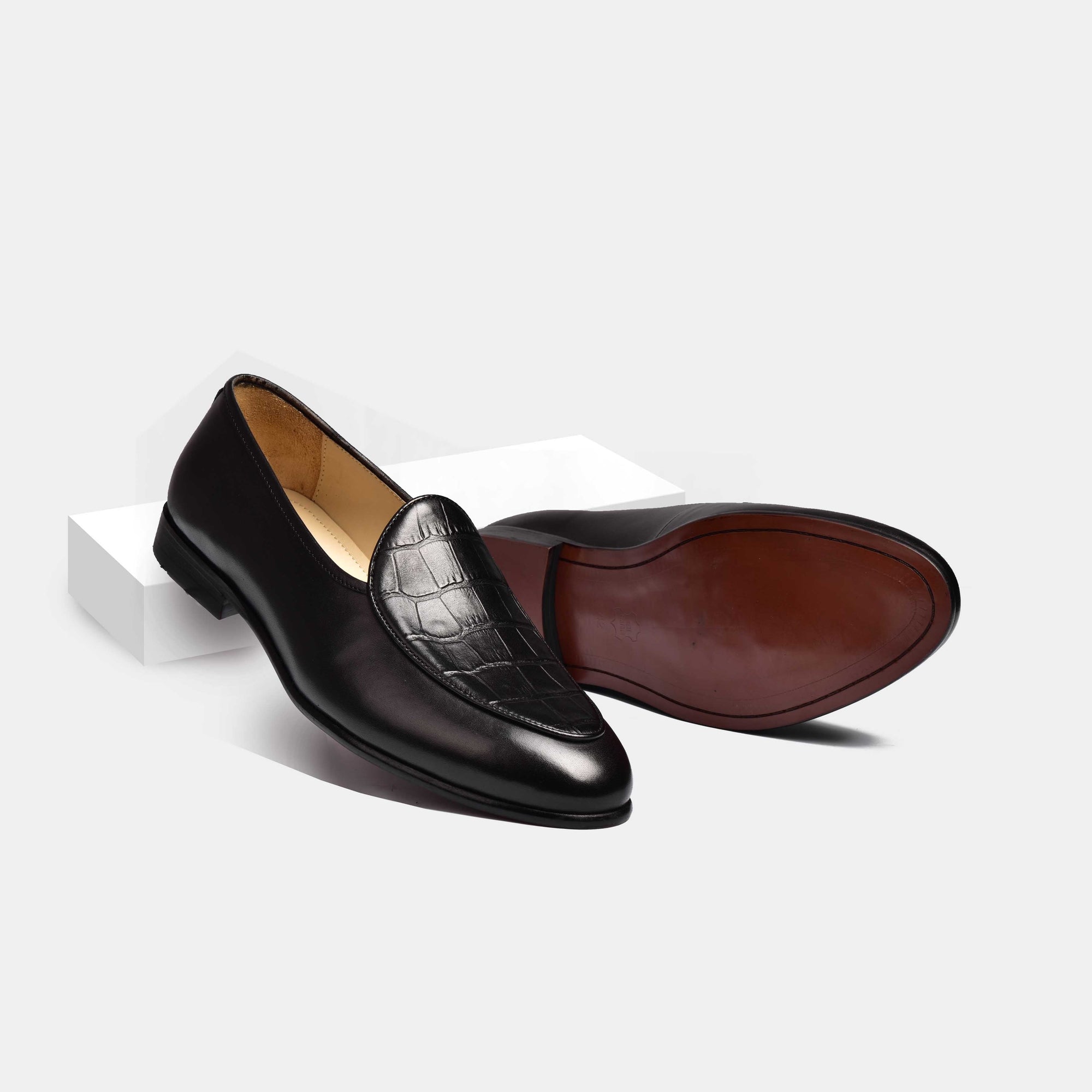 Pair of black leather Arno loafers with crocodile-embossed vamp, shown from side and sole.