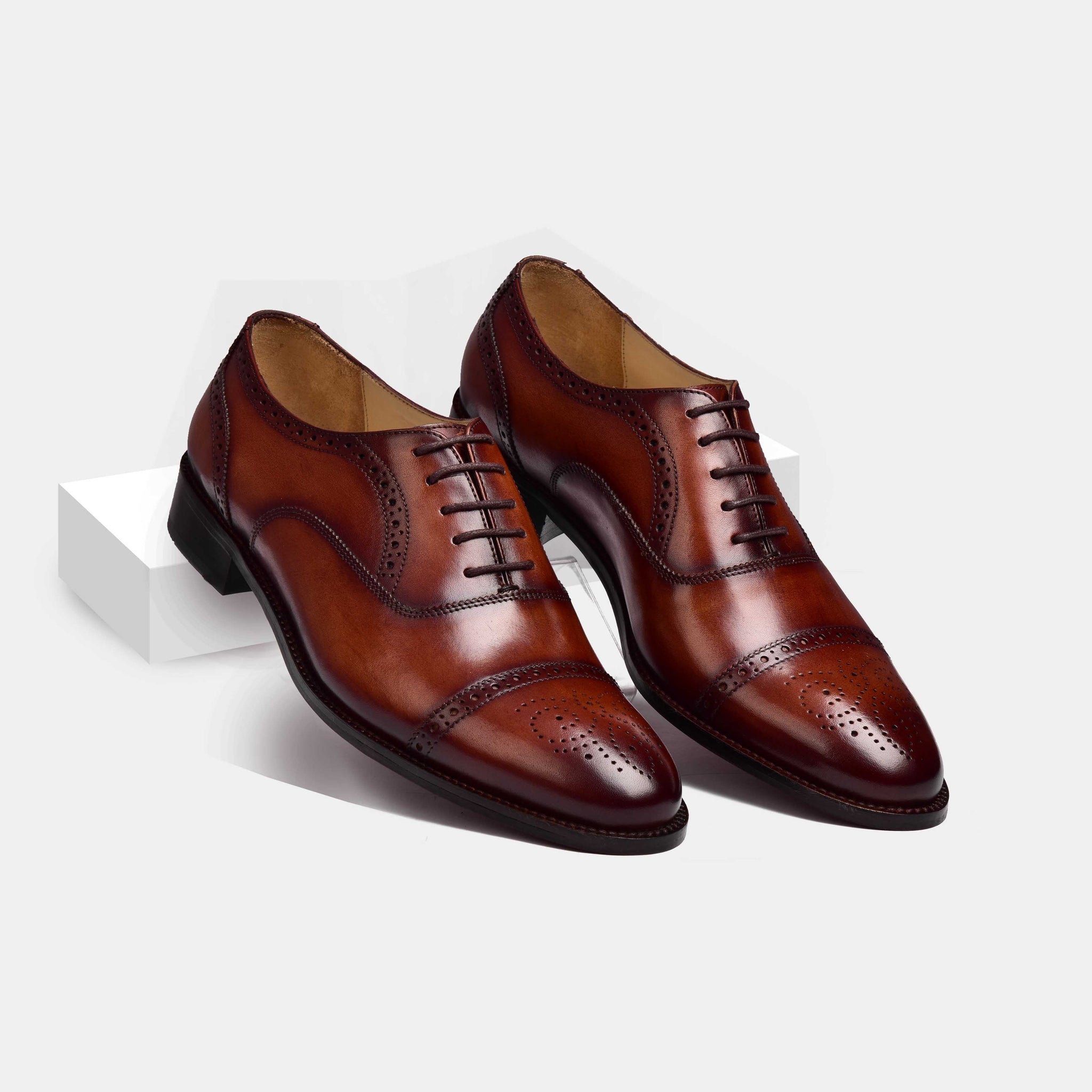 Pair of Steven Brogue Cap Toe Lace Ups in brown leather with decorative perforations, showcasing their classic design.