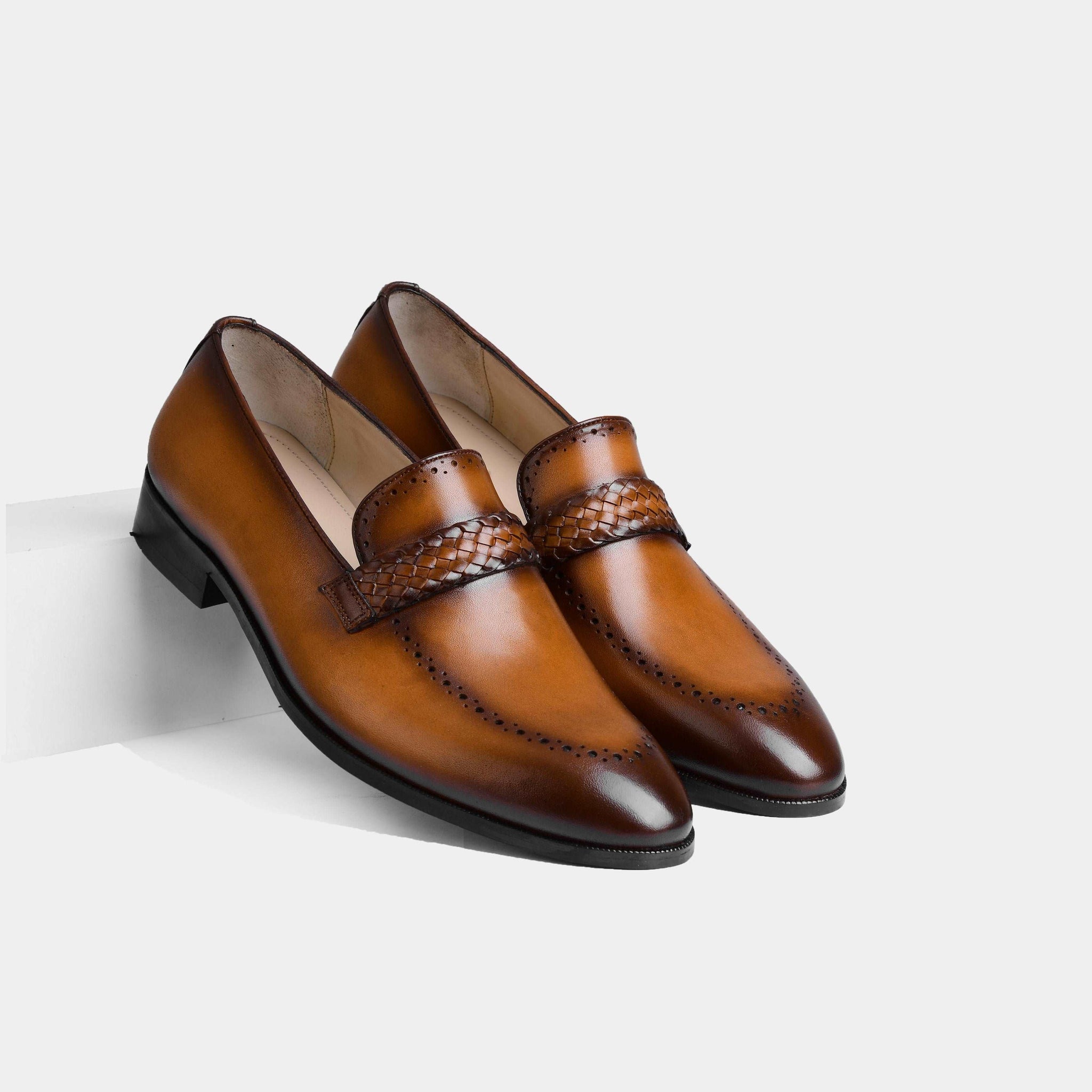 A pair of Alex Tan Leather Loafers in tan brown leather, featuring a woven strap detail and a classic brogue design.