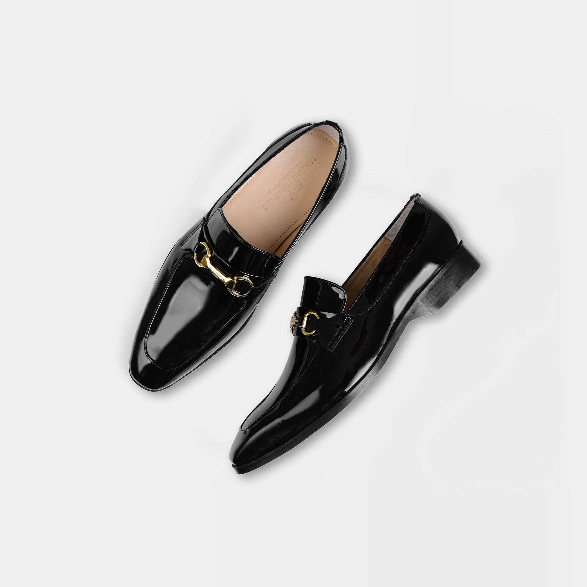 Pair of black Santos Patent Leather Loafers with gold buckle accents, shown from above on a white background.