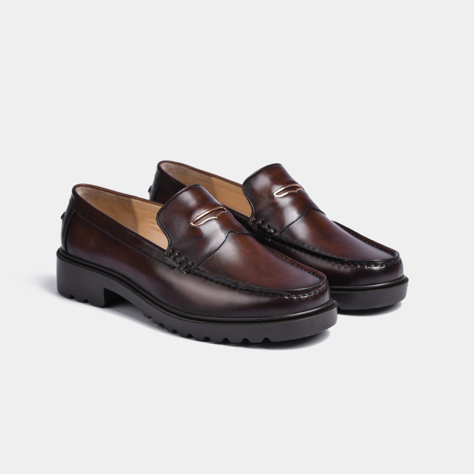 A pair of brown leather loafers with a gold accent on the vamp and chunky black Solesculpt Lite soles.