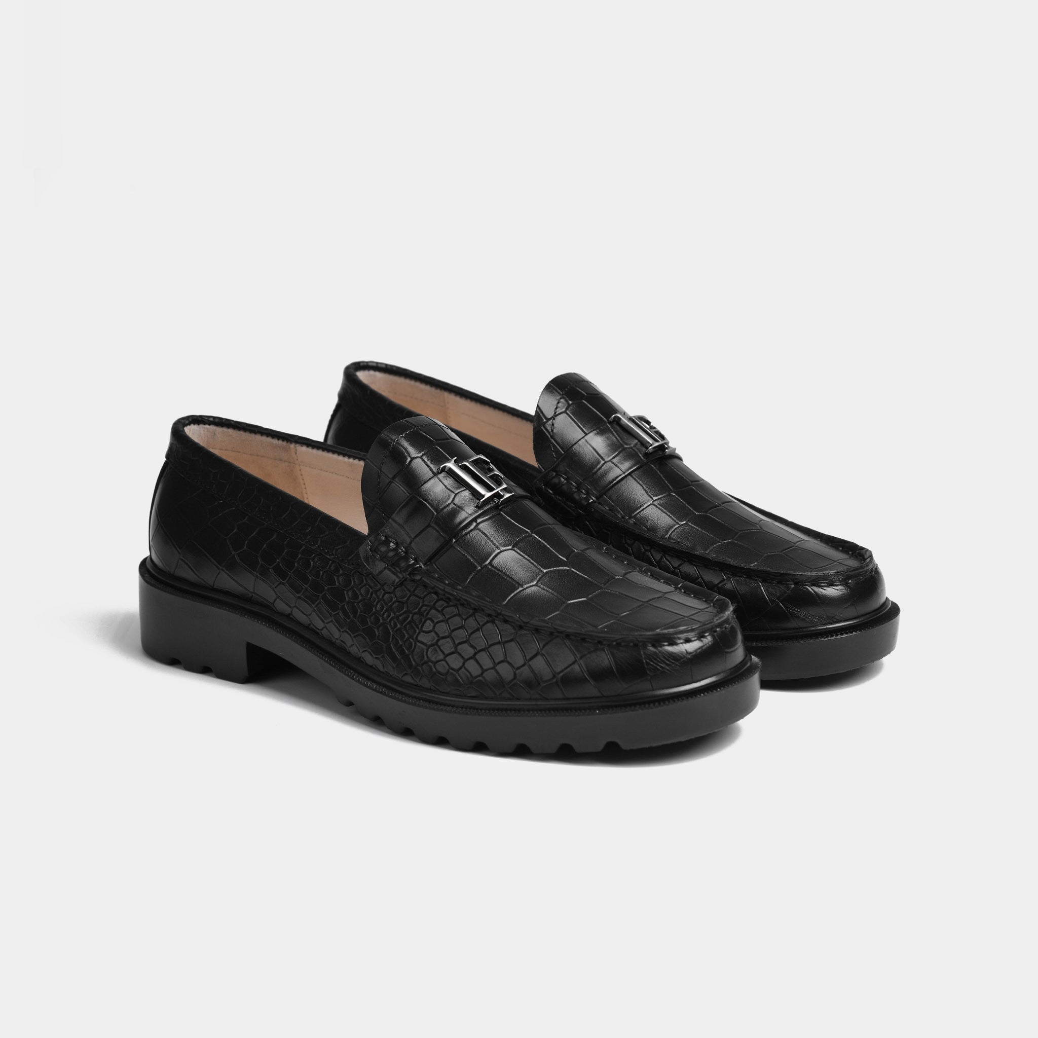 Pair of black croc leather loafers with a silver buckle detail and chunky soles.