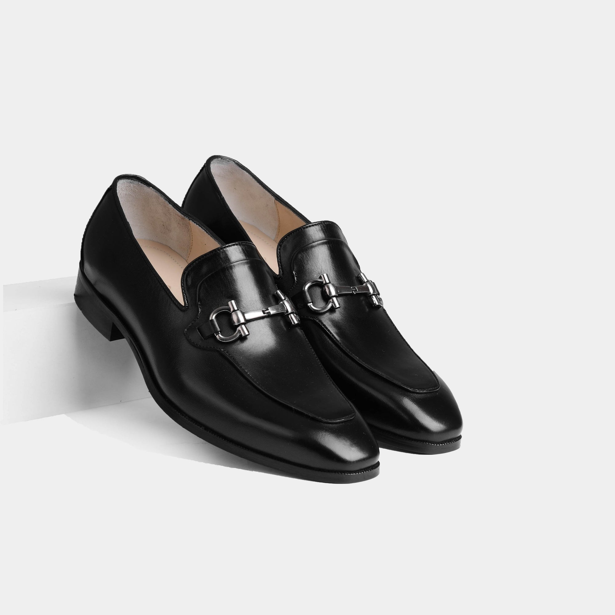 Pair of Arin Black Leather Loafers with a silver buckle accent on a white background.