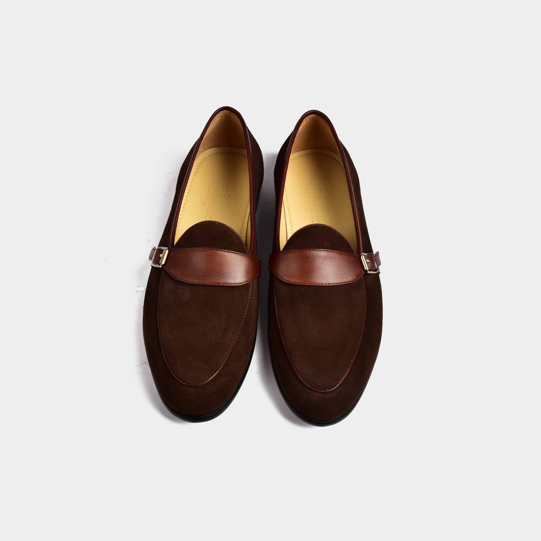 Pair of brown suede Arno Loafers with a leather buckle strap across the front.