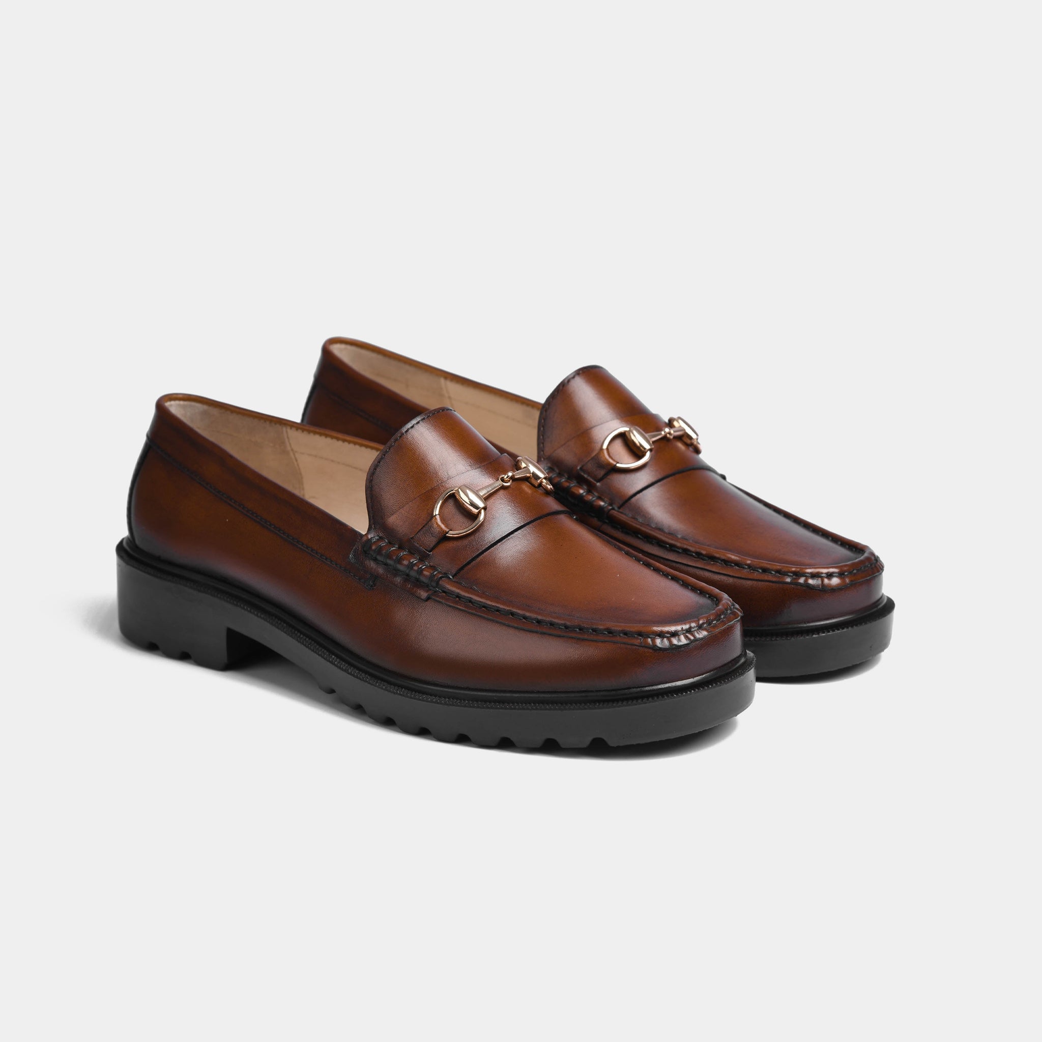 Pair of brown leather bit loafers with gold snaffle hardware and chunky black Solesculpt Lite soles.