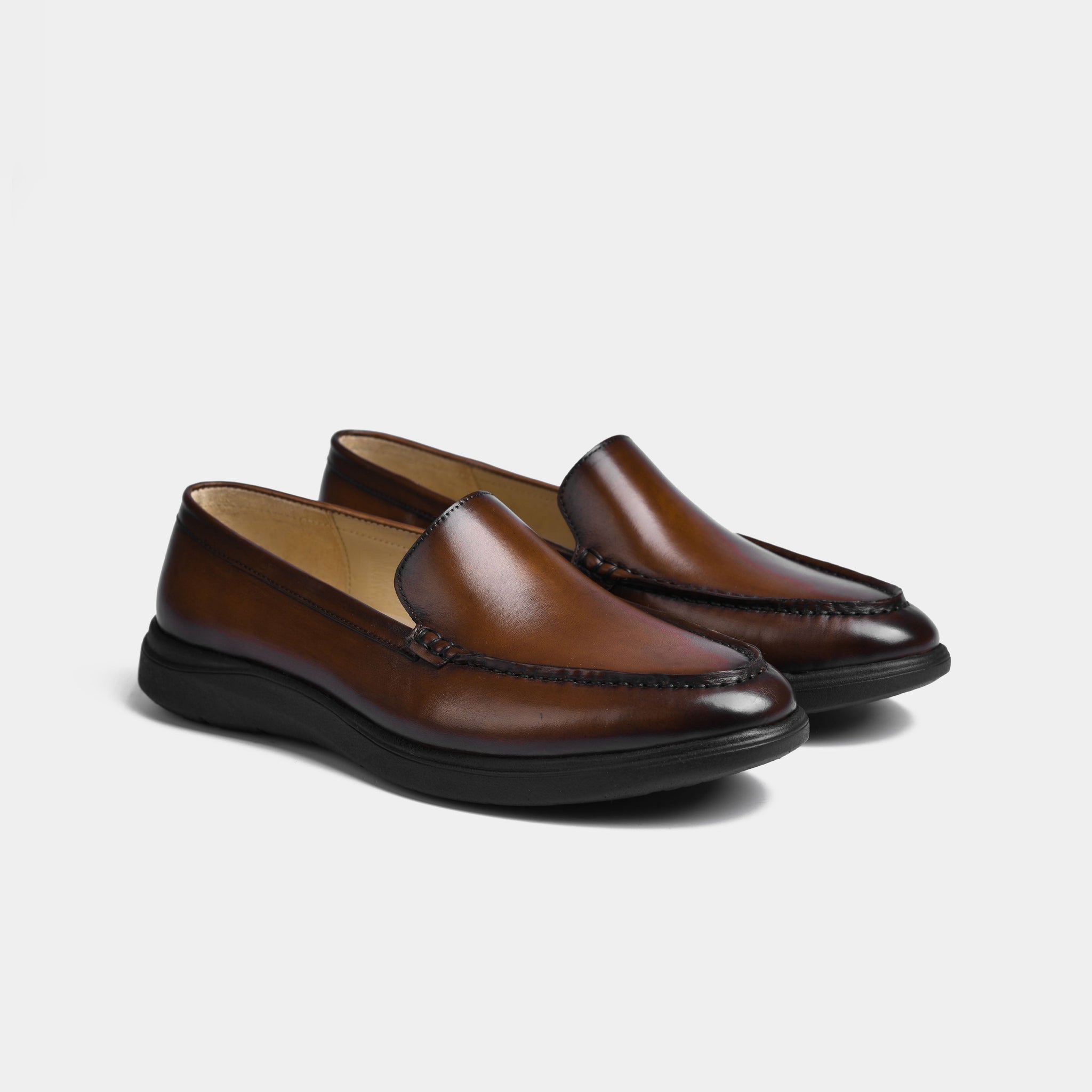 Pair of brown patina leather slip-on shoes with a sleek, modern design. Comfortable and stylish footwear.