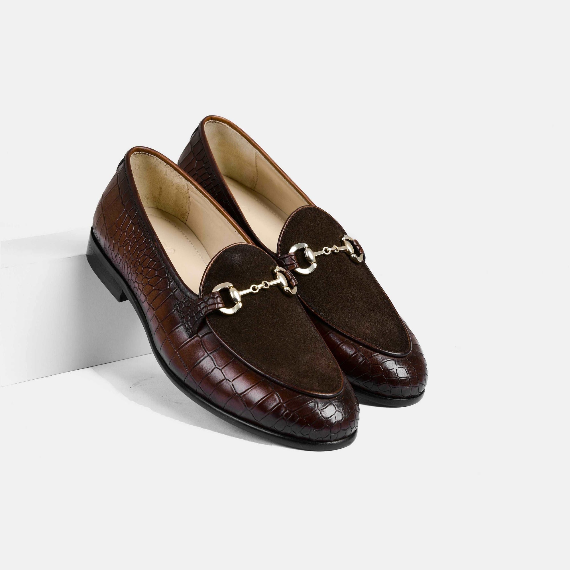 A pair of Azura Brown Leather Loafers with a crocodile skin texture, suede upper, and gold buckle detail.