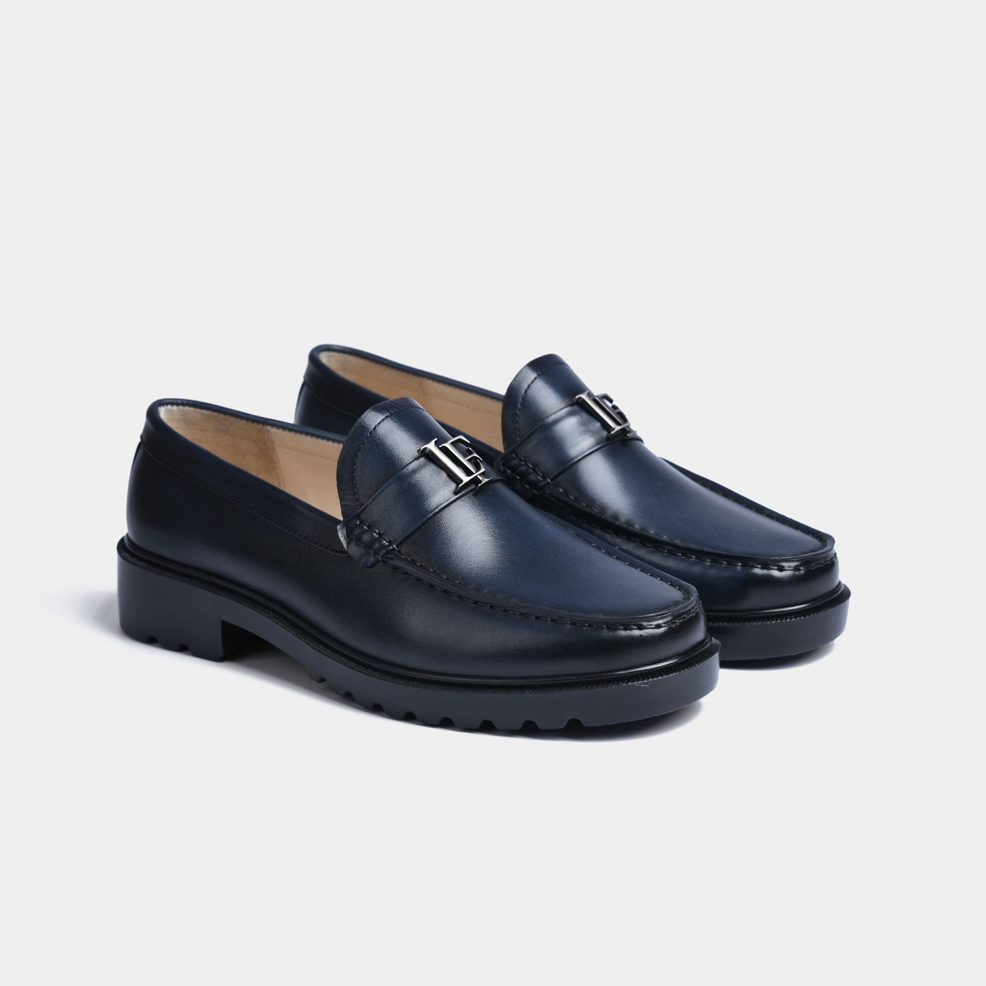 Pair of navy blue leather loafers with silver buckle accent, showcasing the Blue Lf Timeless Leather Loafers with Solesculpt Lite technology.