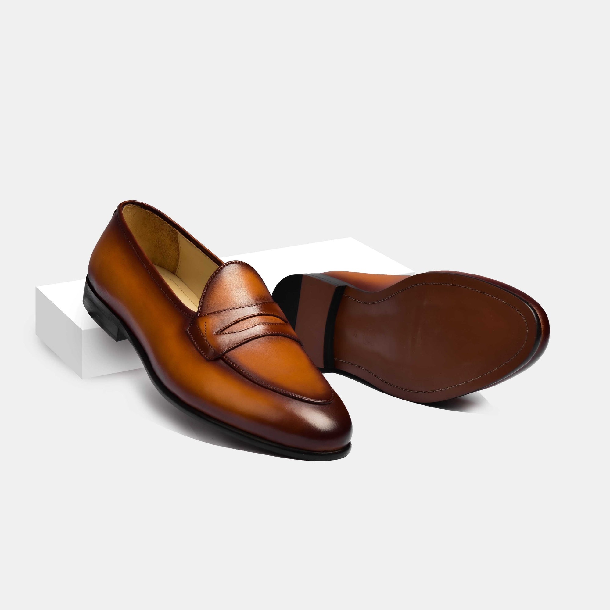 Pair of tan handpainted patina Arno loafers for men, featuring a classic penny loafer design and hand-stitched detailing.