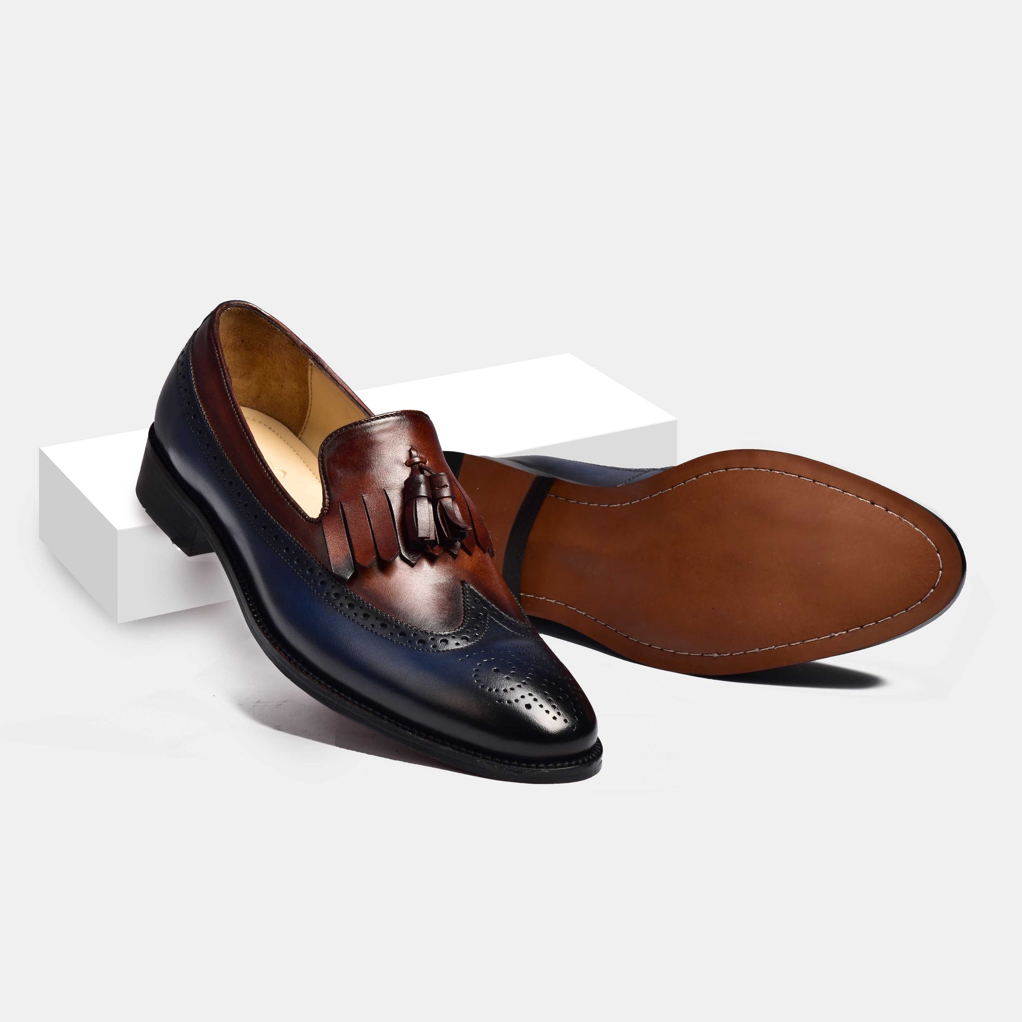 Stylish dual tone leather loafers with tassel detail. These men's dress shoes feature brogueing and a sleek silhouette.