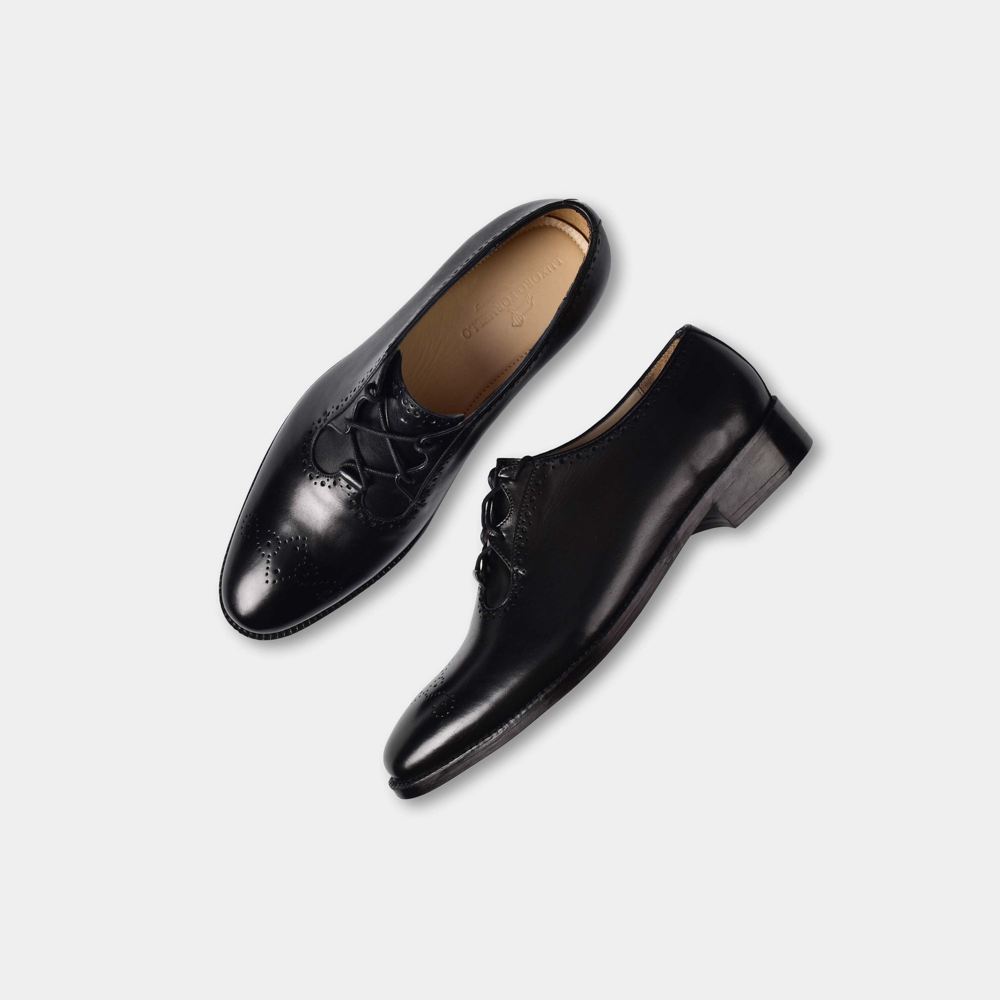 A pair of Ronald Lace Ups, sleek black leather oxford shoes with brogue detailing, shown from a top-down angle on a white background.