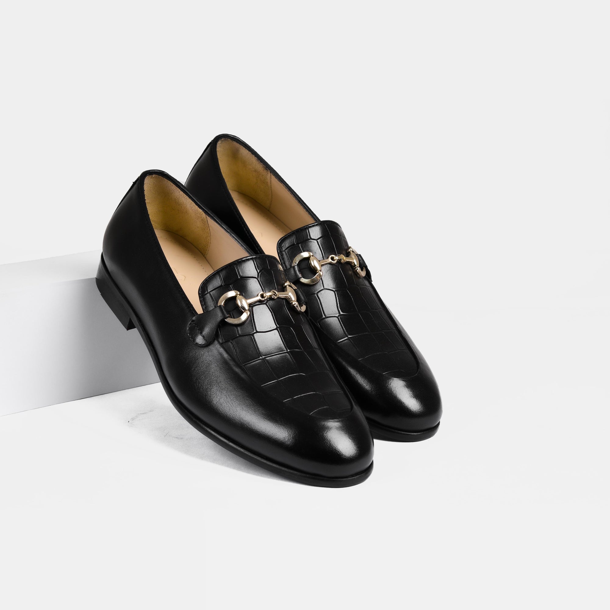 Pair of Damian Black Loafers with gold buckle accent, showcasing their sleek, crocodile-embossed leather.