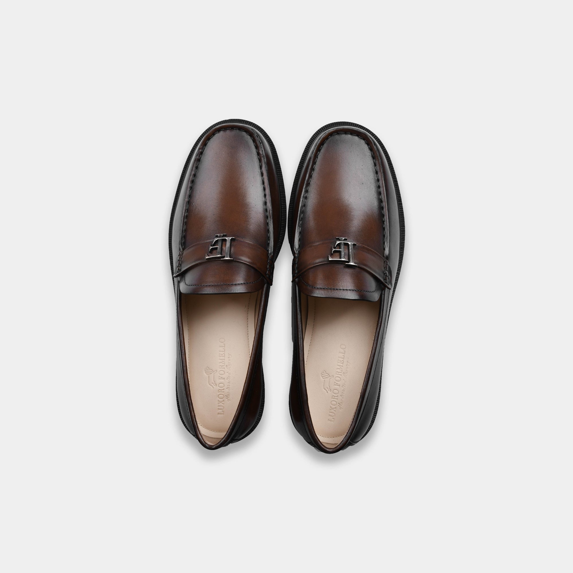 Pair of brown leather loafers with a silver buckle detail, shot from above on a white background.