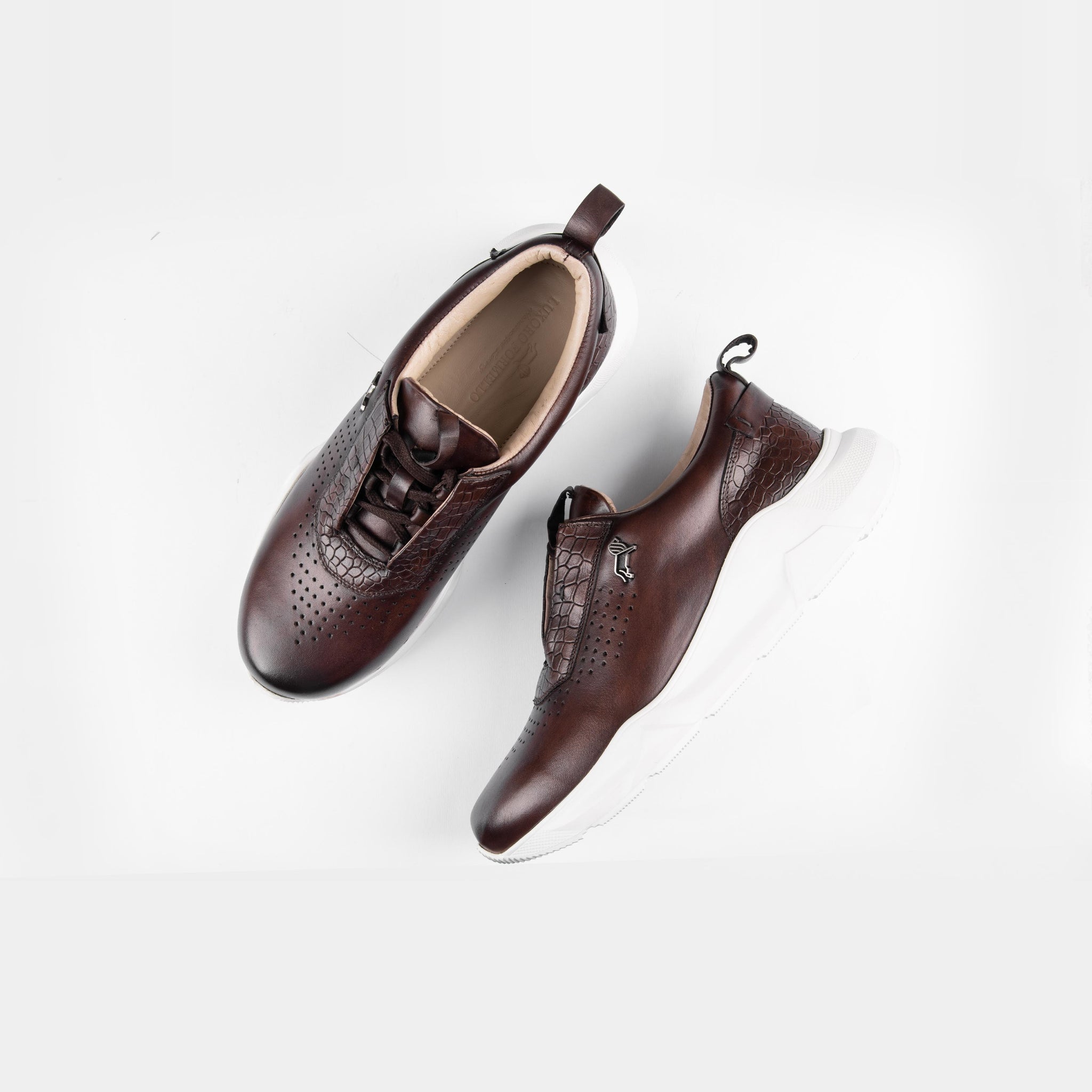 Pair of Arine brown leather sneakers for men with white soles and lace-up closure, styled on a white background.