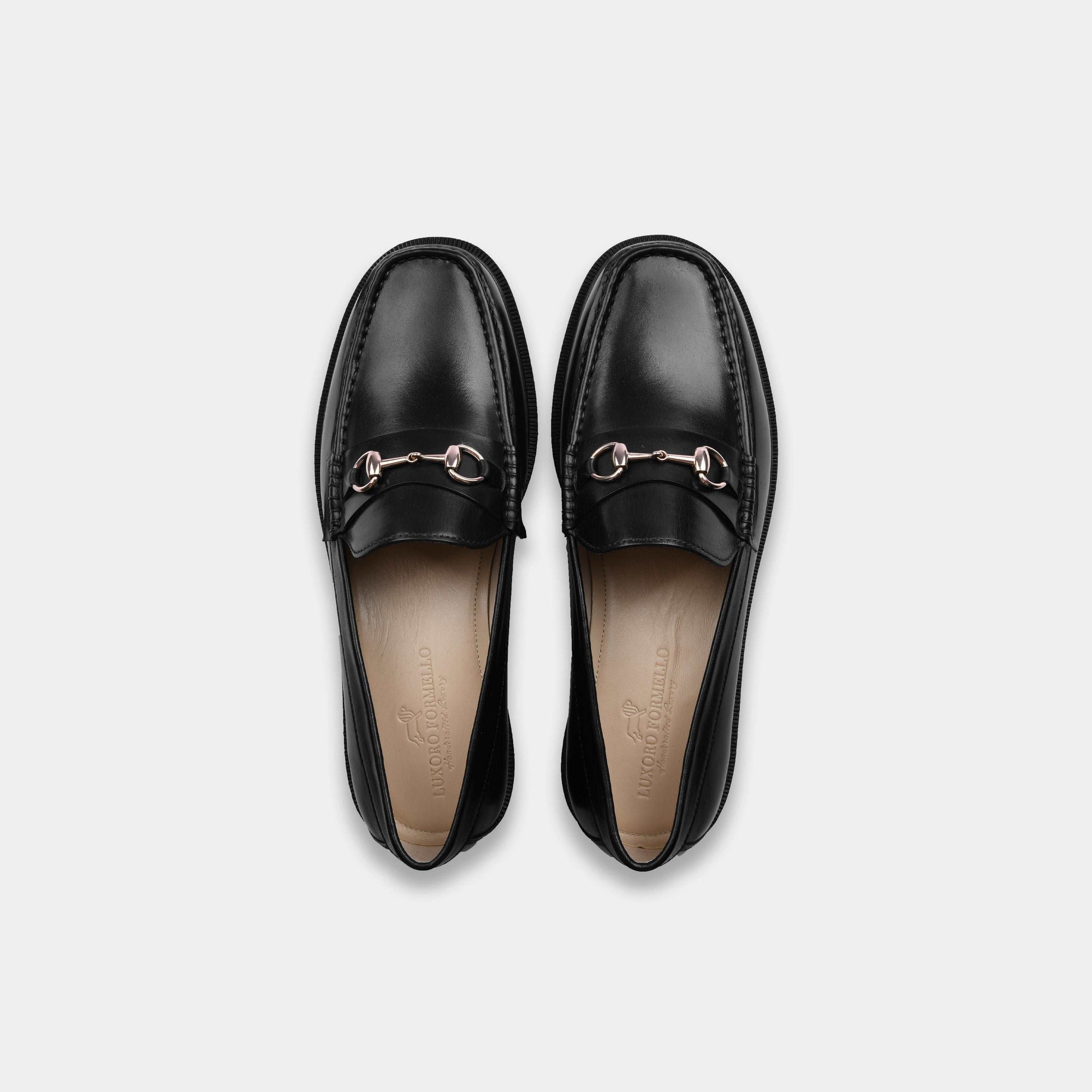 Pair of black leather loafers with gold buckle accent, top view. Solesculpt Lite construction for comfort.