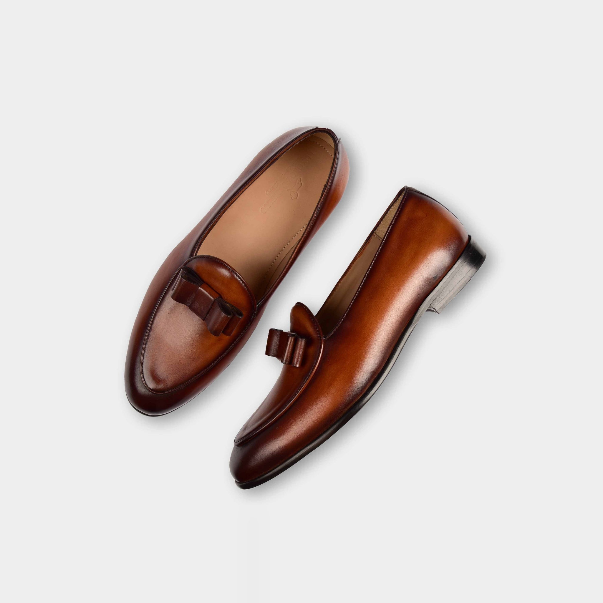 A pair of Arno Loafers in brown patina leather with a stylish bow-tie silhouette.