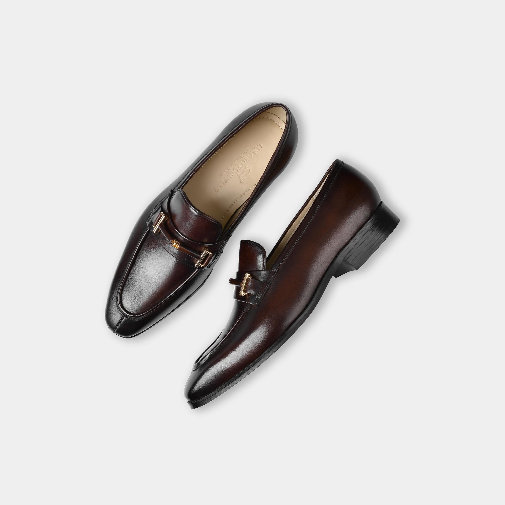 Adelmo Obsidian Brown Leather Loafers with a gold buckle detail, shown from above on a white background.