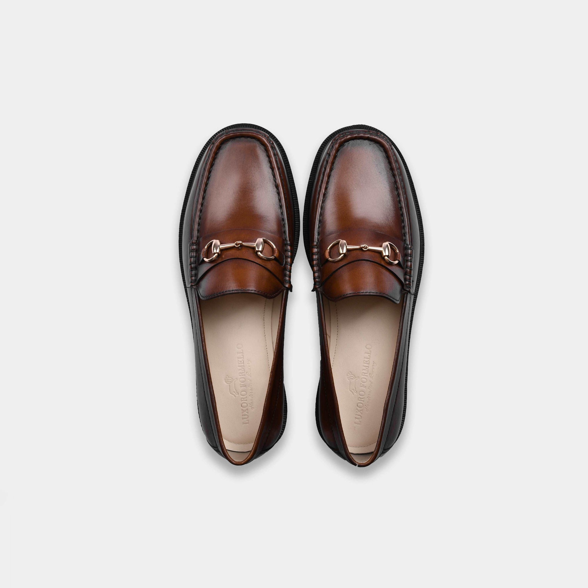 Pair of brown bit leather loafers with gold buckle detail, top view. Solesculpt Lite construction.