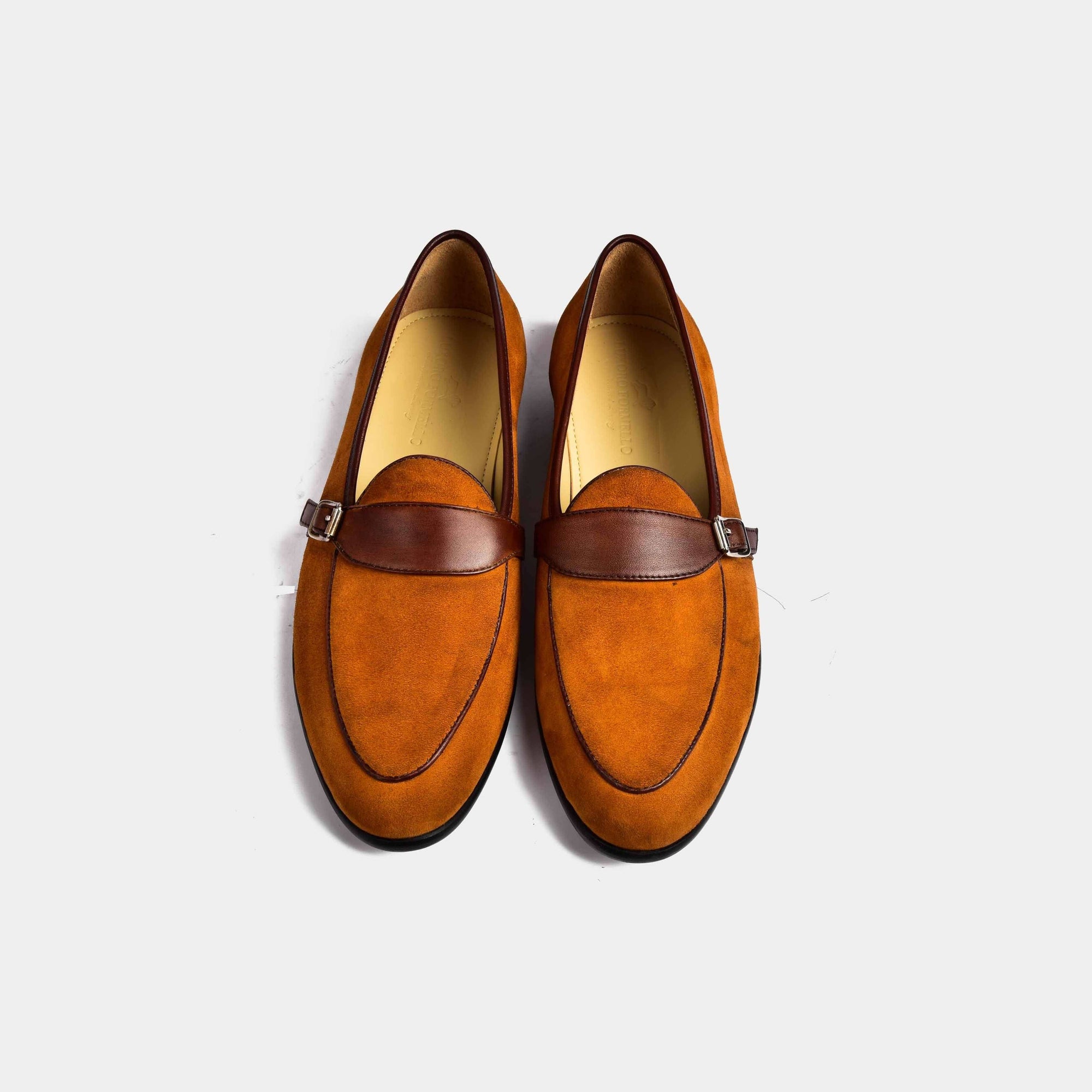 Tan suede Arno loafers with a brown leather buckle strap across the vamp.