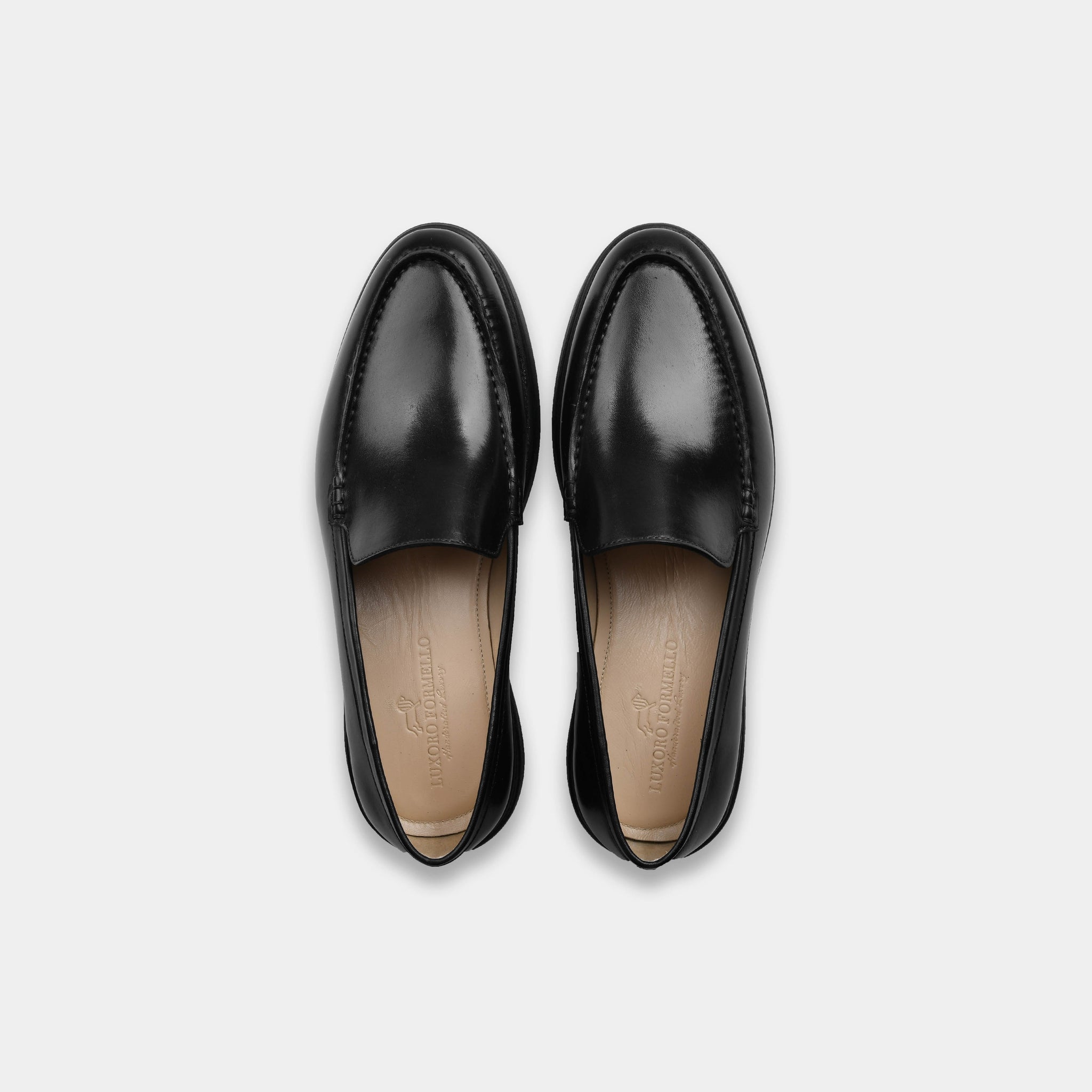 Pair of black burnished leather slip-on shoes, Aero-Flex model, top view showing the sleek design and leather lining.