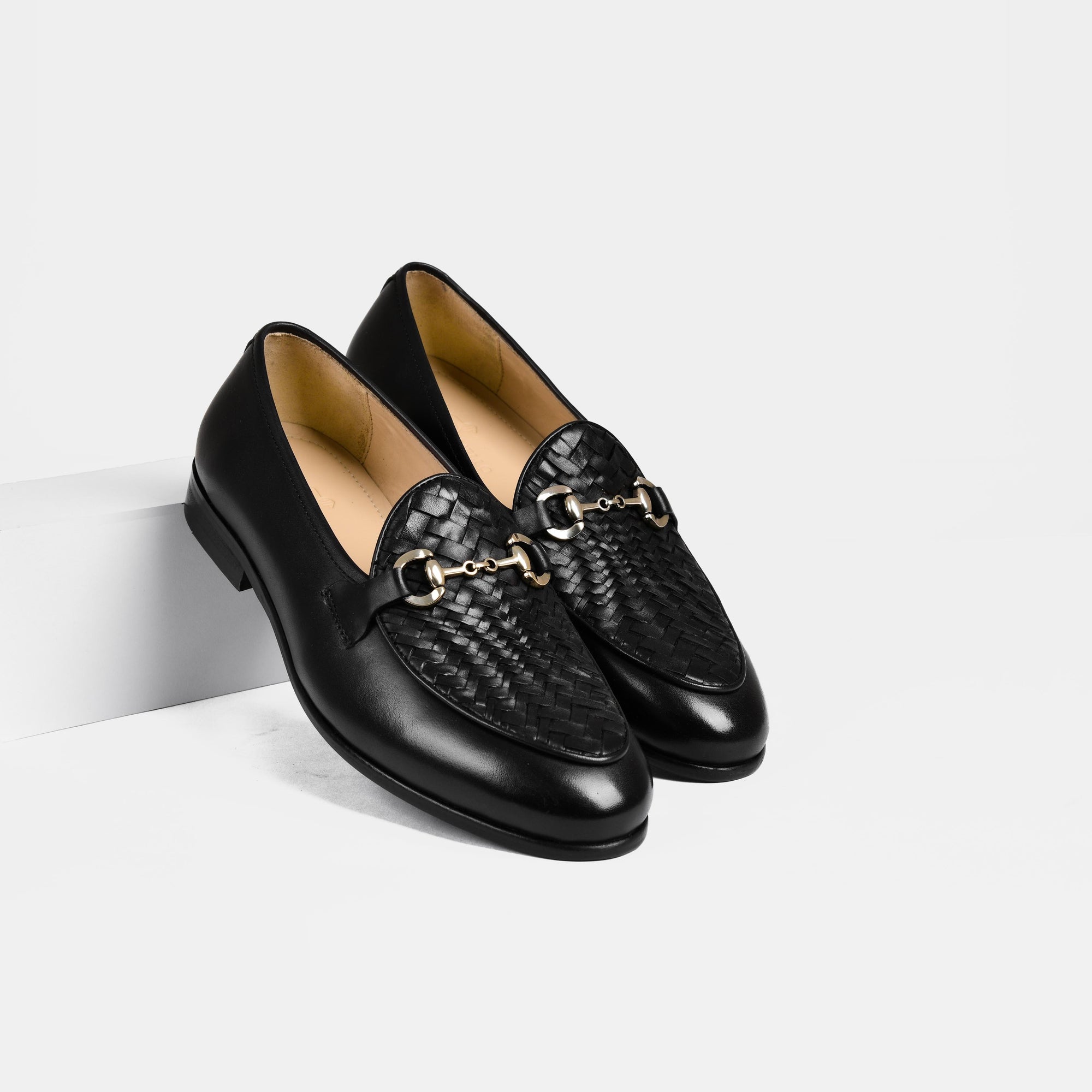 Pair of Santiago Weaved Black Leather Loafers with a woven detail and gold buckle accent on a white background.