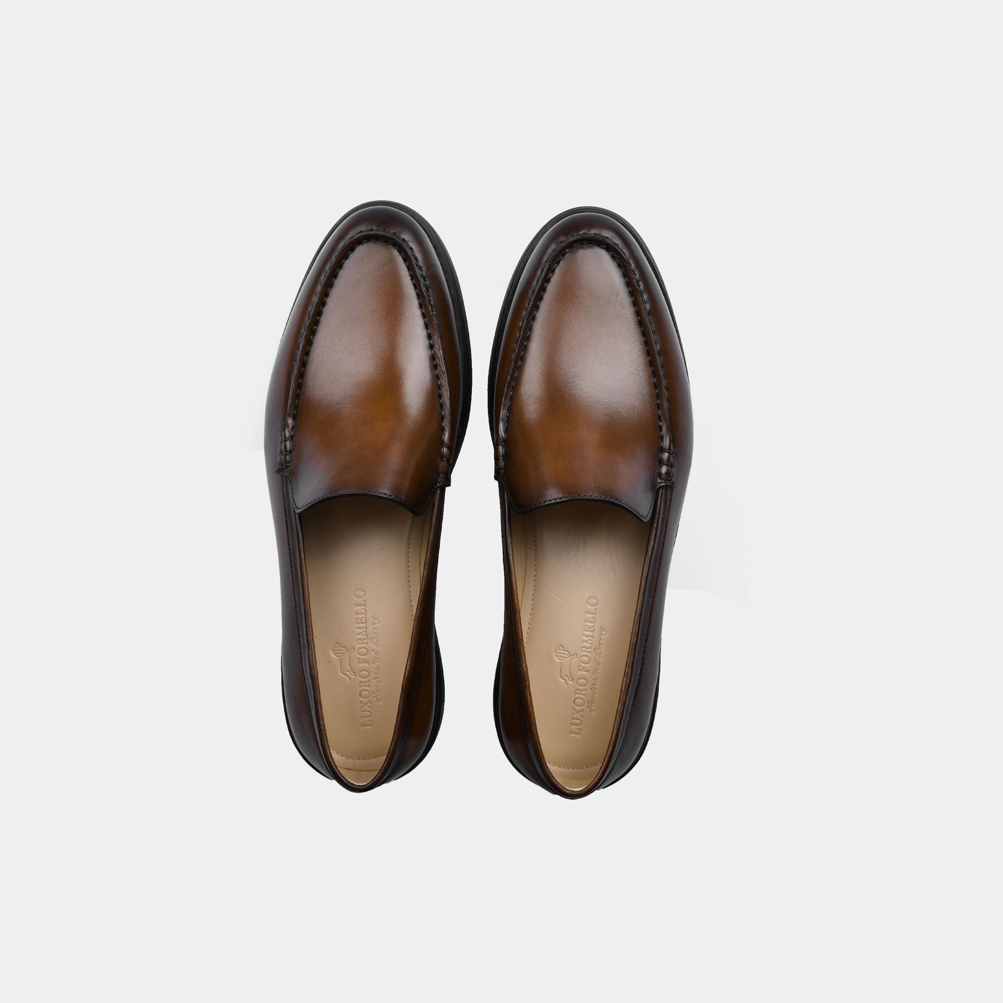 Pair of brown patina leather slip-on shoes for men, top view.