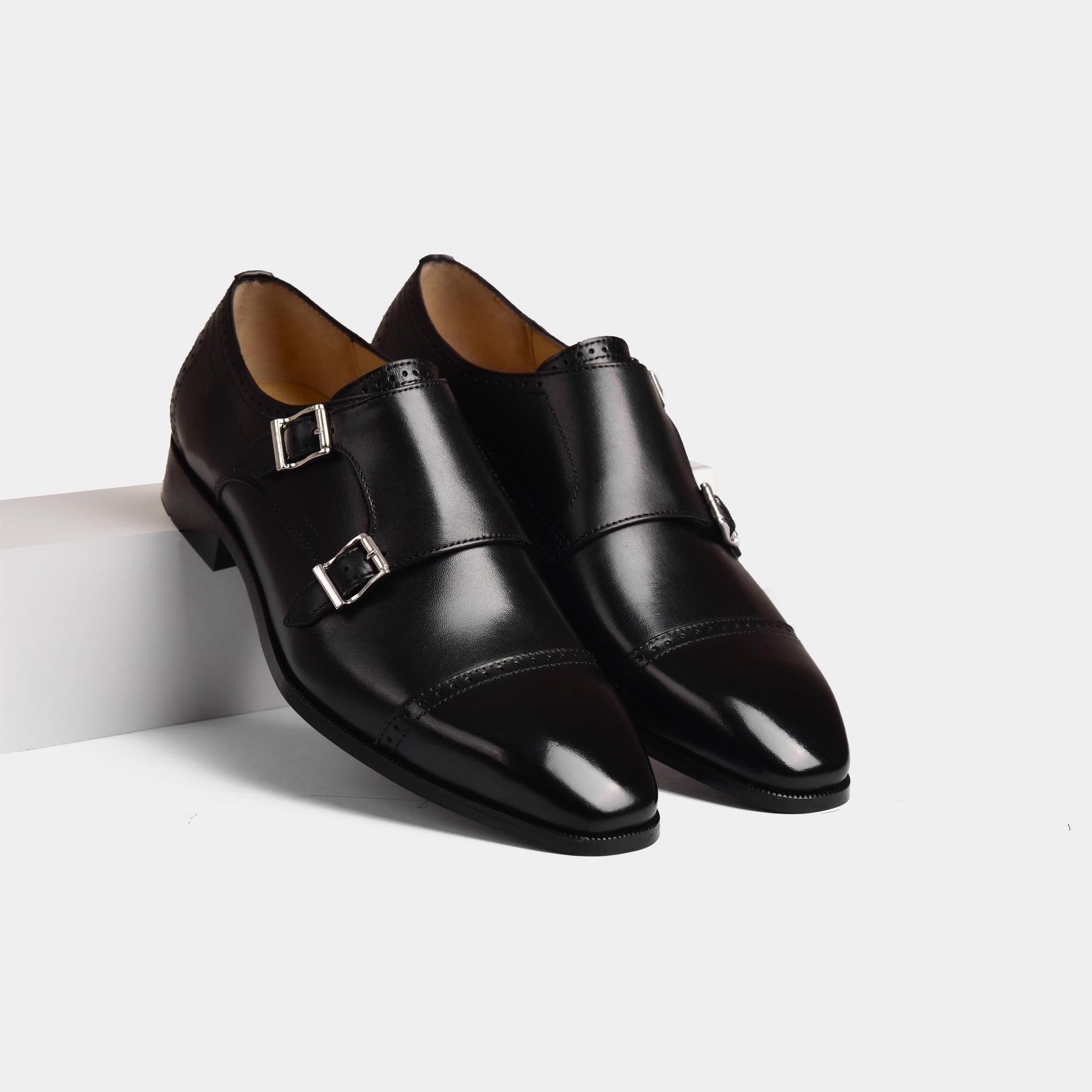 Pair of Nacario Black Monk Strap shoes, crafted from polished black leather, featuring double buckle closures and brogue detailing.