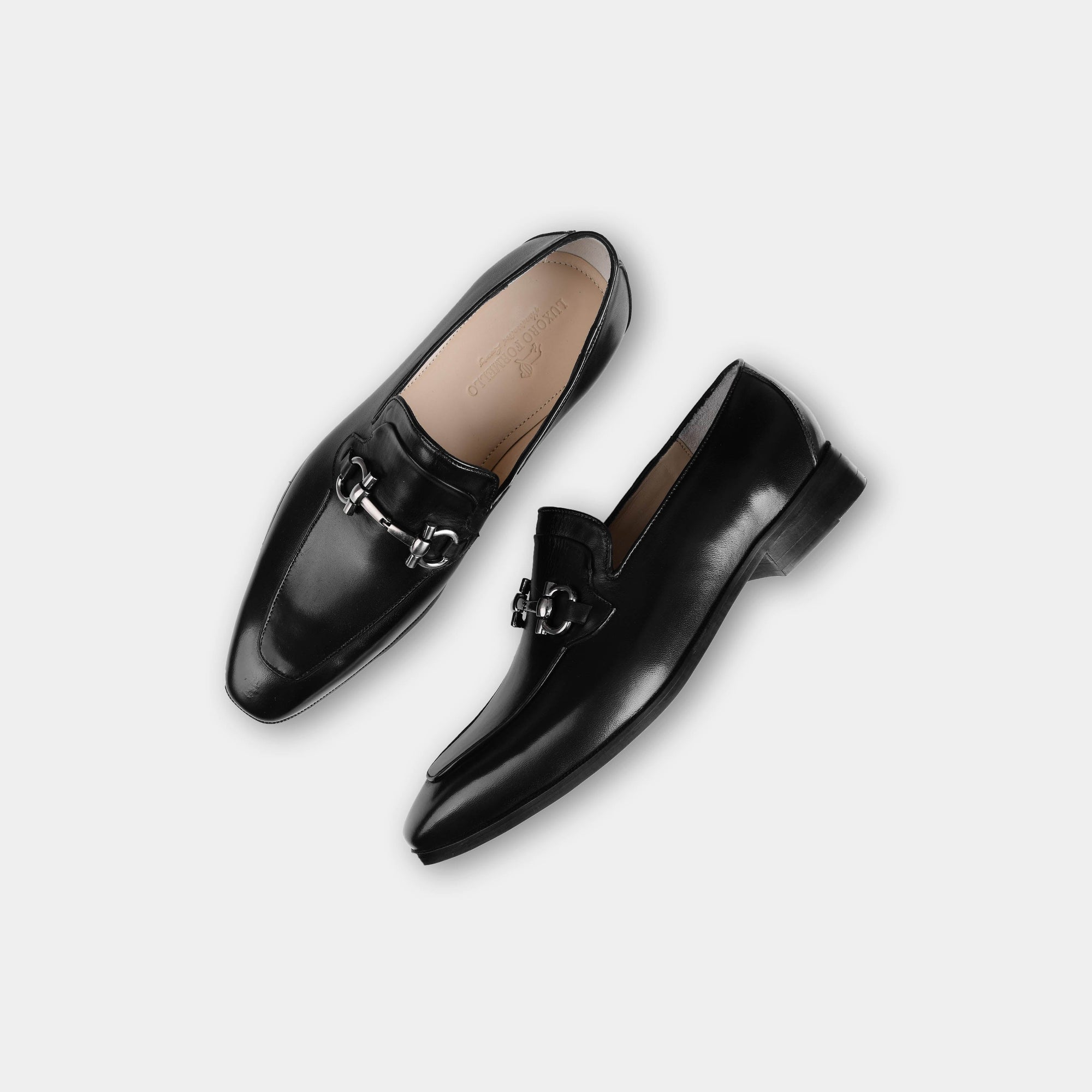 Pair of Arin Black Leather Loafers with silver buckle accent, shown from above on a white background.