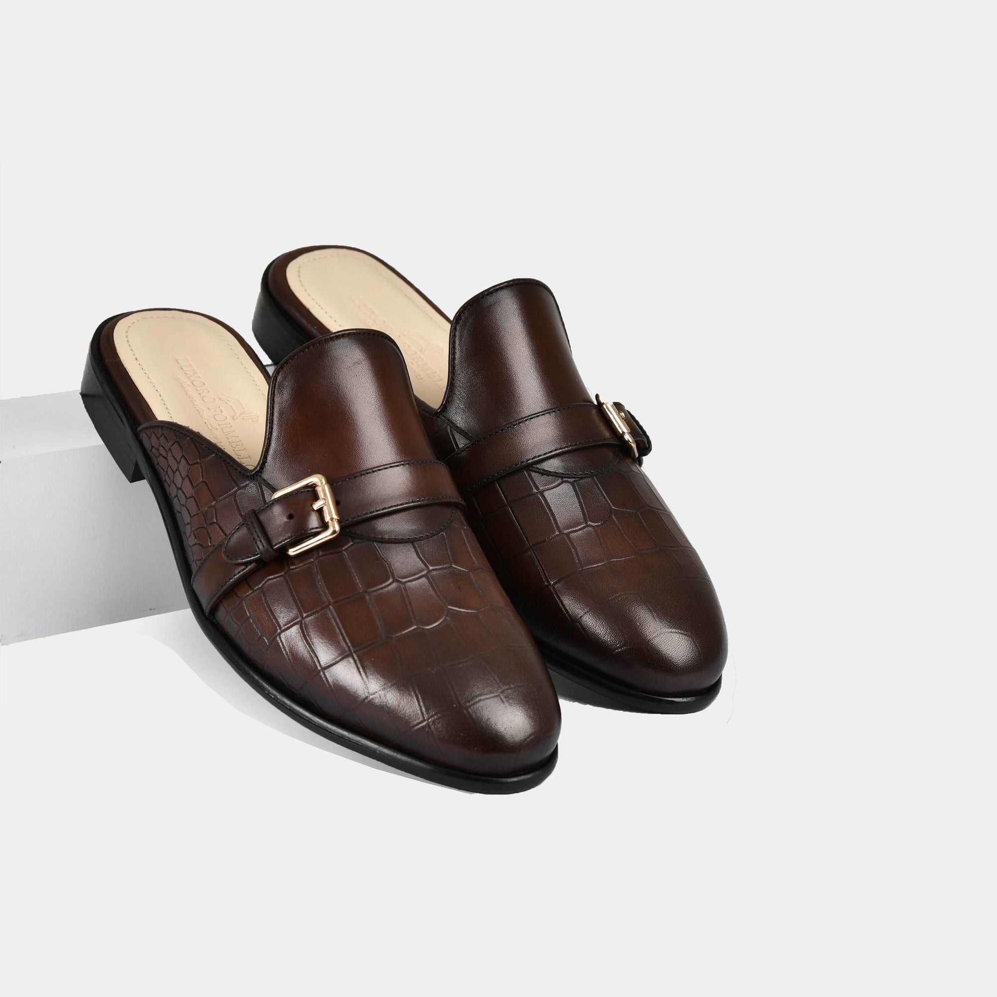 Pair of brown leather mules with a single buckle strap and a crocodile-embossed pattern.