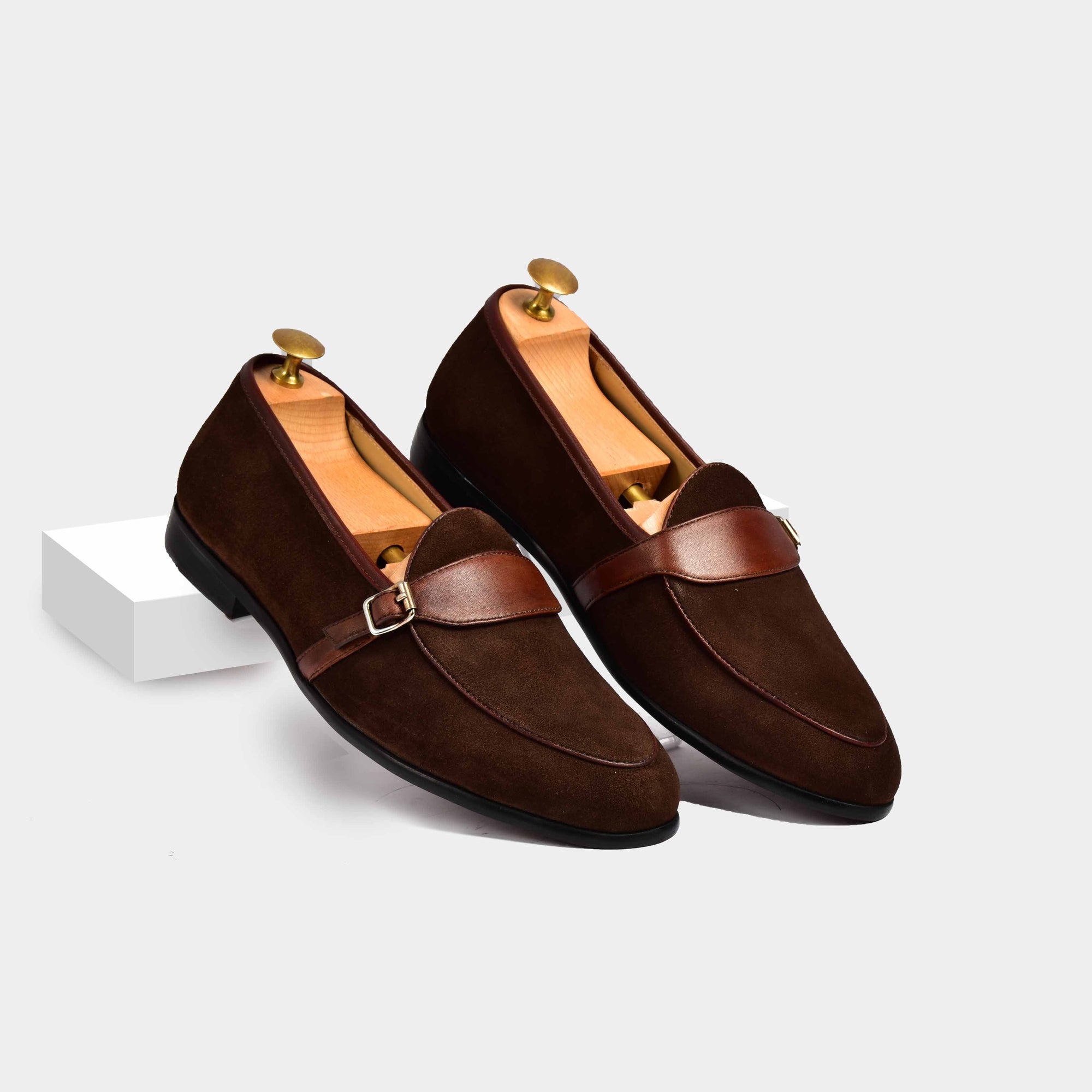 Pair of brown suede Arno loafers with a leather buckle strap across the front.