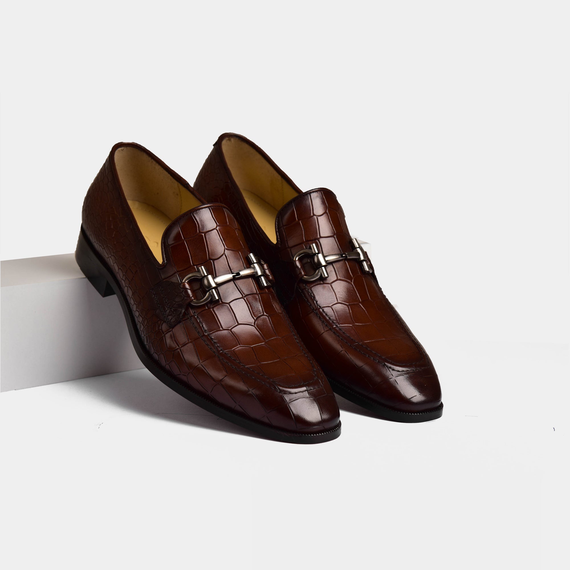 Pair of Liora Brown Leather Loafers with a crocodile skin texture and silver buckle detail.