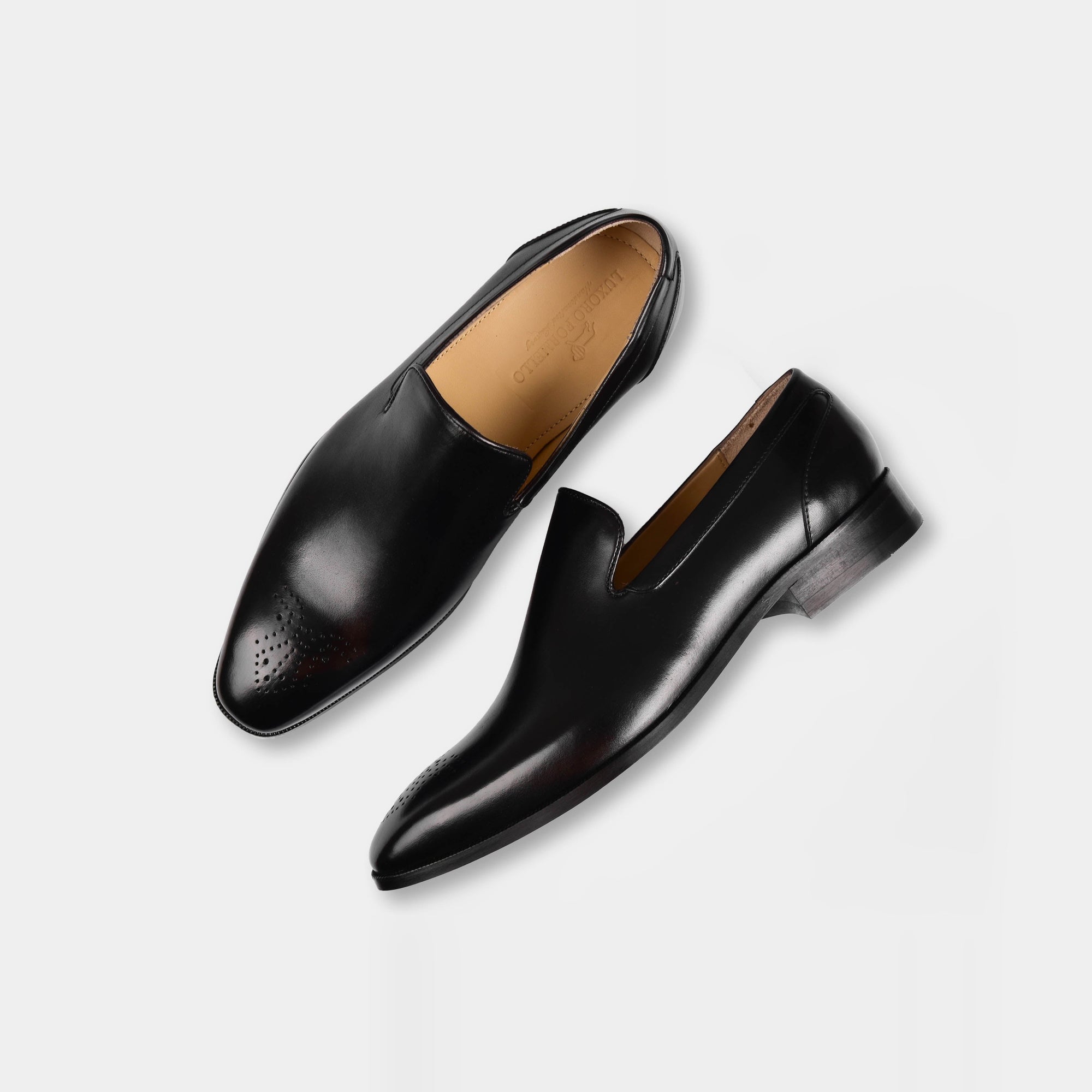 Pair of Madrid Black Leather Loafers with perforated toe caps, showcasing their sleek and polished design on a white background.