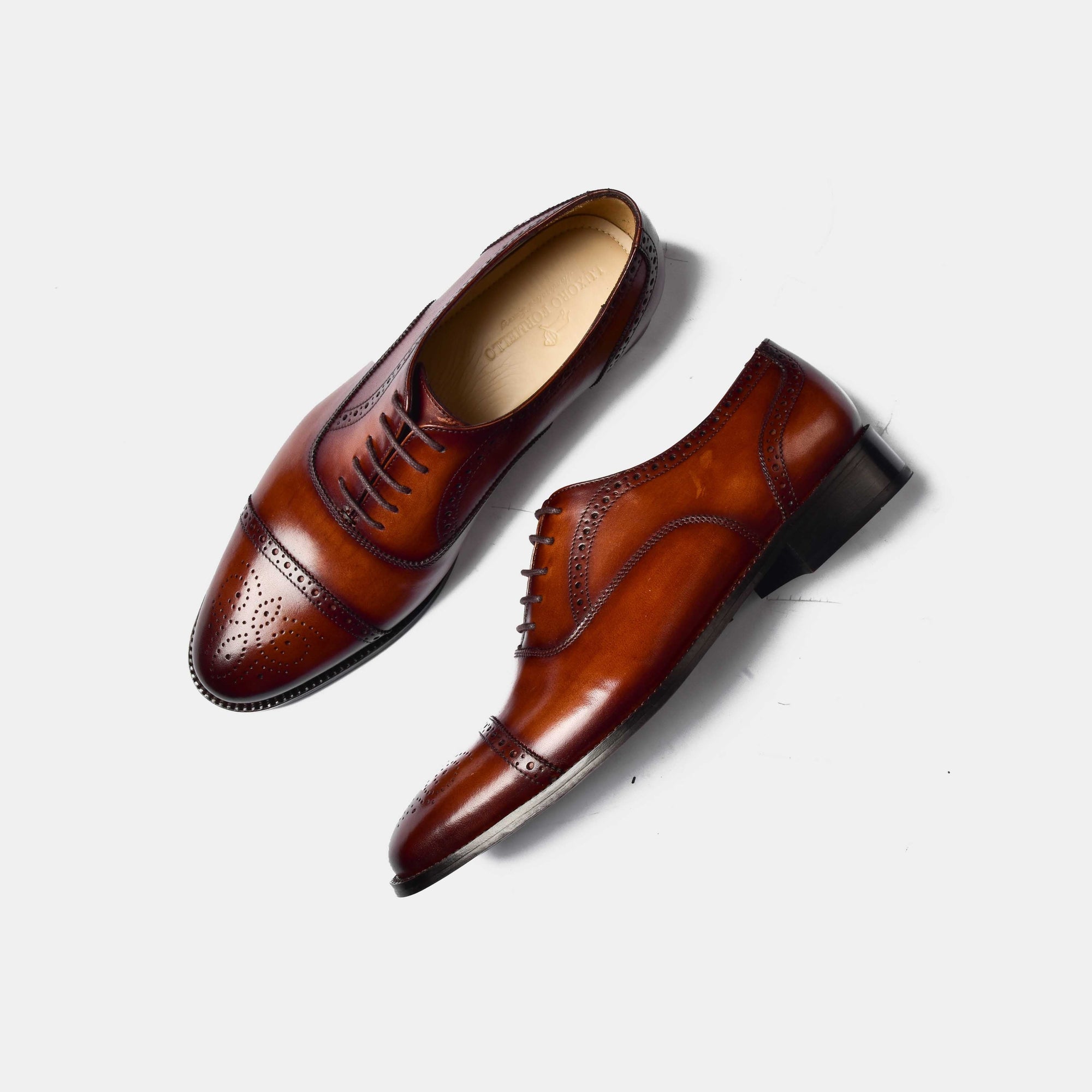 Pair of Steven Brogue Cap Toe Lace Ups in brown leather, showcasing their detailed broguing and cap toe design on a white background.