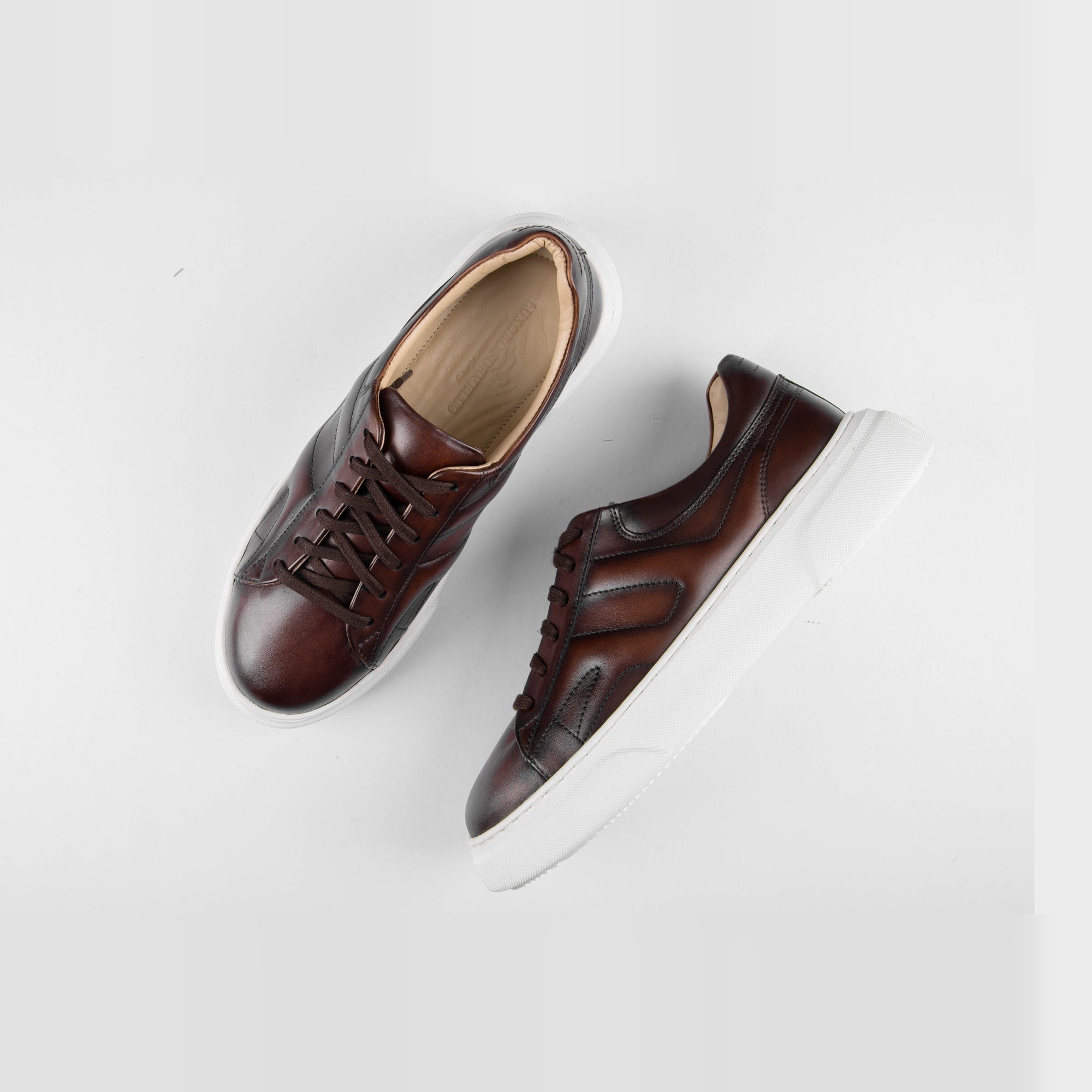 Pair of Luxoro Signature brown leather sneakers with white soles, positioned on a white background.