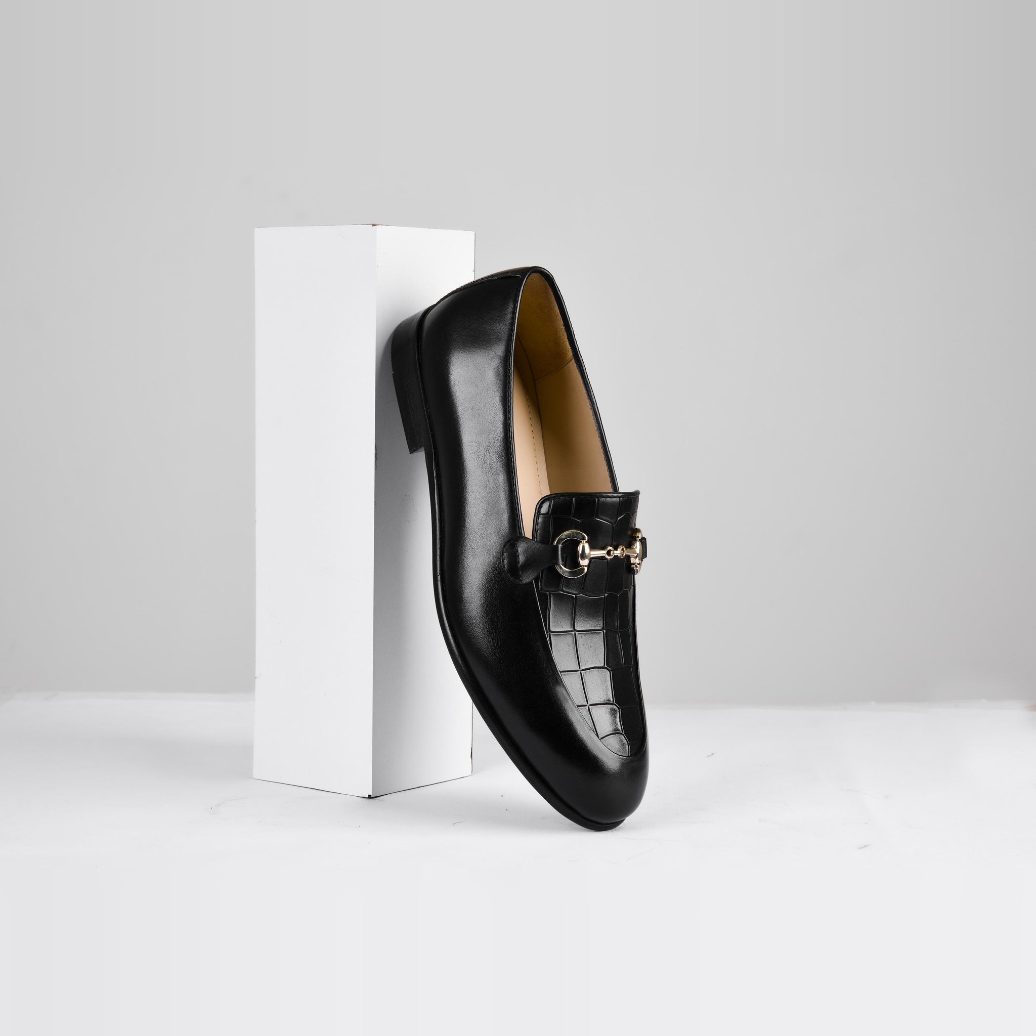 Pair of Damian Black Loafers, featuring a gold buckle accent, elegantly positioned against a white background.