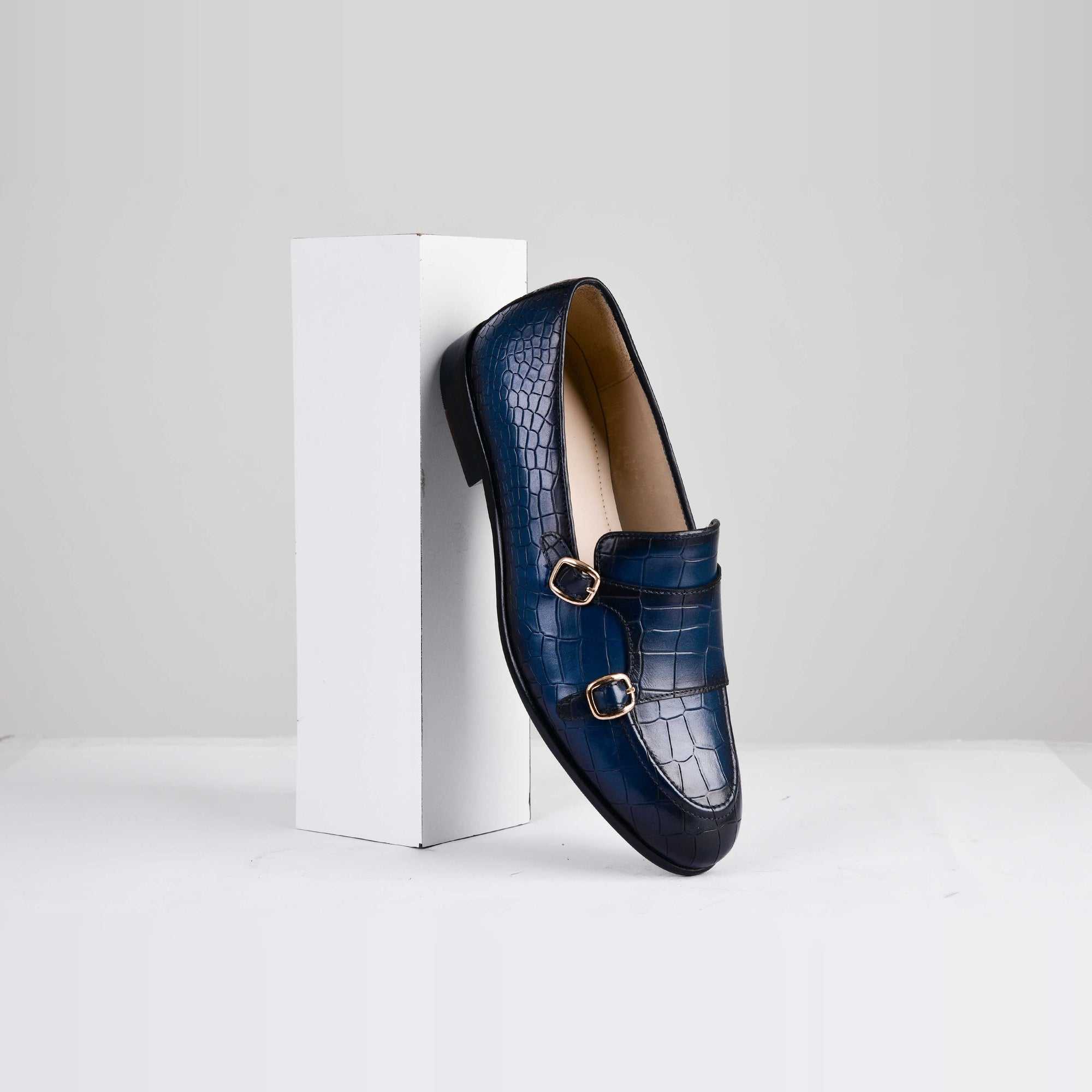 Blue crocodile leather monk strap shoe with gold buckles, titled "Valeria Croc Blue Leather Monk Straps."