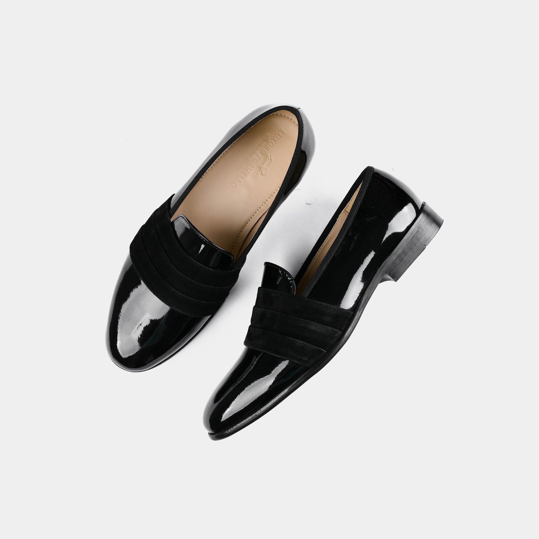 Pair of Delmar Black Patent Loafers with a suede strap across the top, shown from above on a white background.