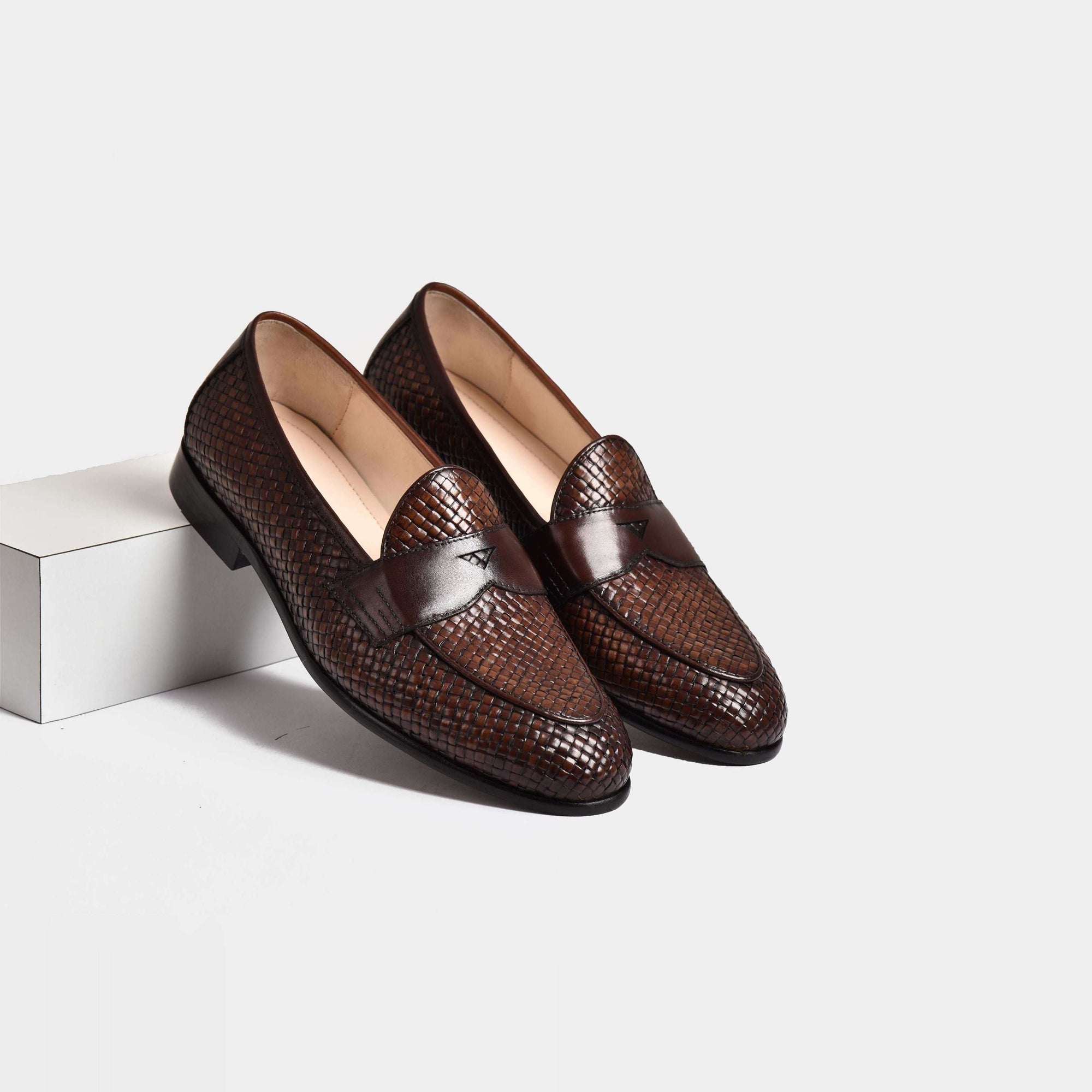 A pair of brown Arno Loafers with a handwoven leather design.