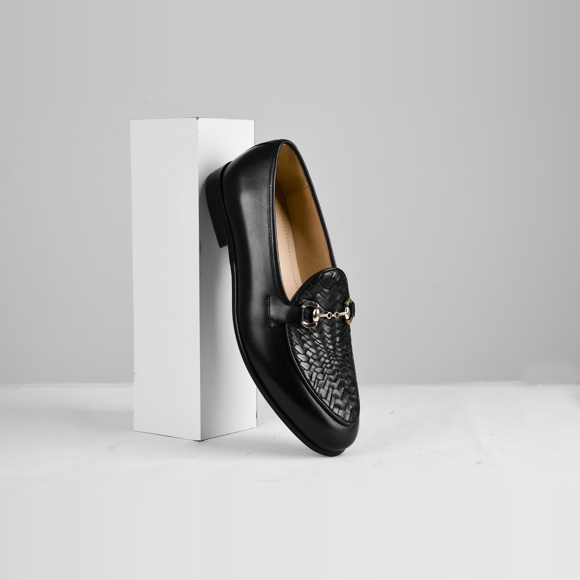 Pair of Santiago Weaved Black Leather Loafers with a gold accent buckle on a white background.