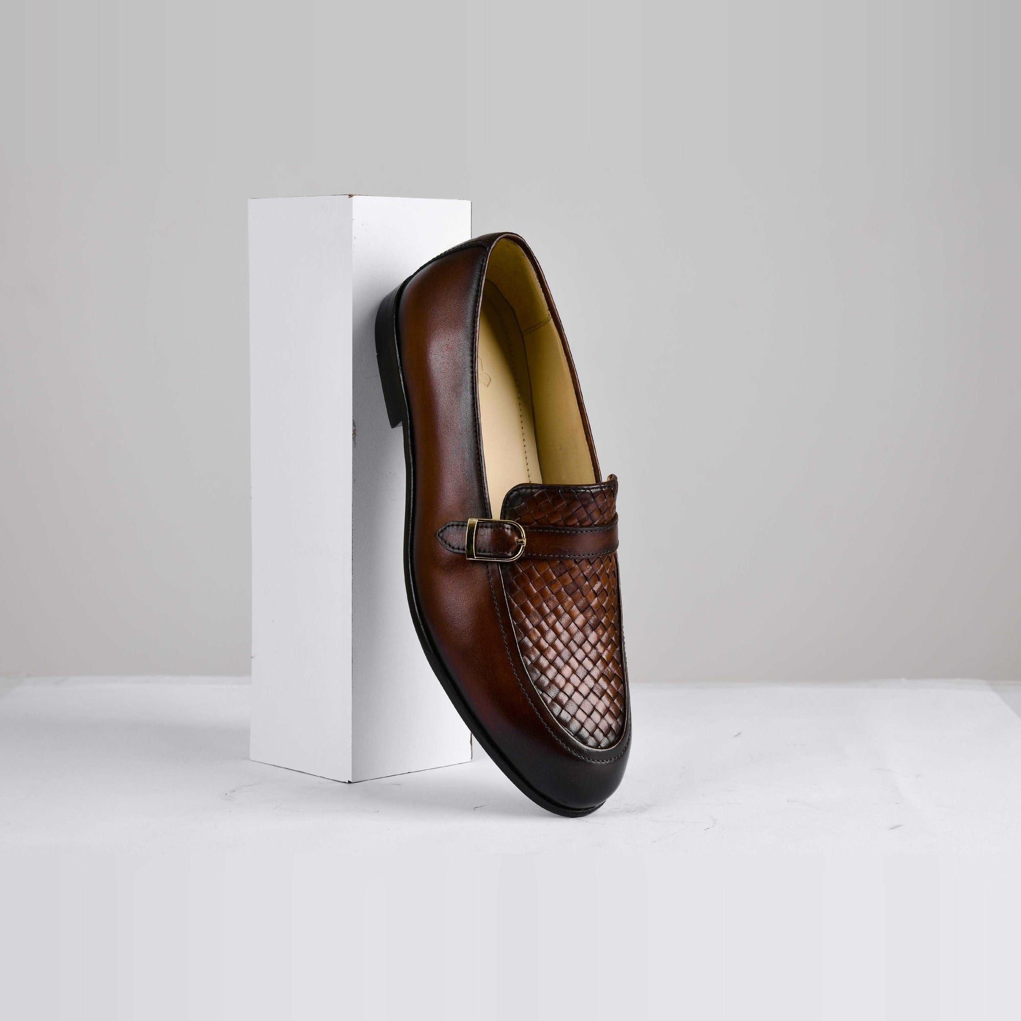 Pair of brown leather loafers with a woven buckle strap, titled Arlow.